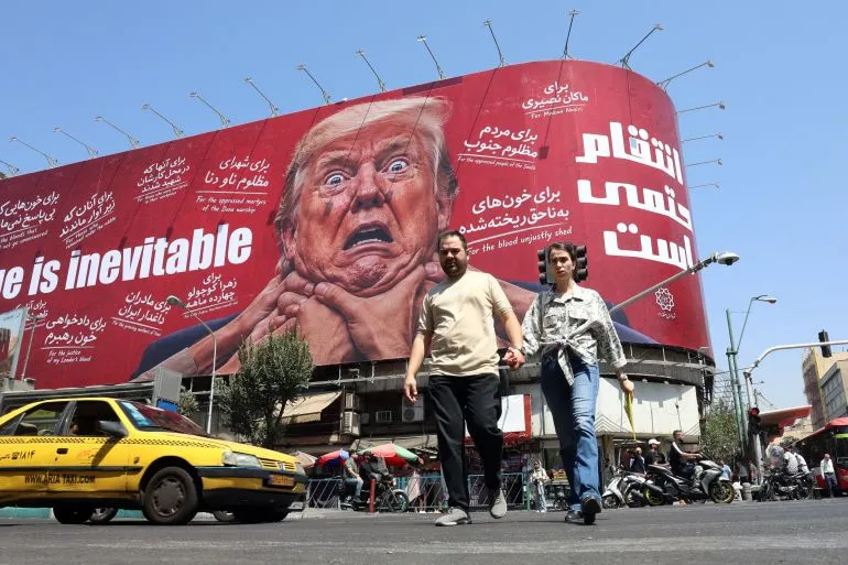 ملصق ضخم في طهران يظهر وجه دونالد ترامب مع عبارات تهديد بالانتقام، يعكس التوترات بين إيران والولايات المتحدة.