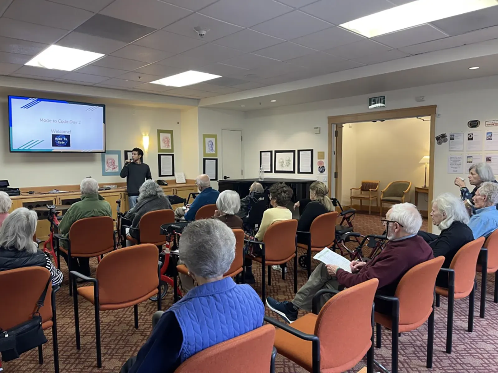 شاؤول يقدم درسًا في البرمجة لكبار السن في مركز للرعاية، حيث يتفاعل مع مجموعة من المتعلمين المهتمين بالتكنولوجيا.