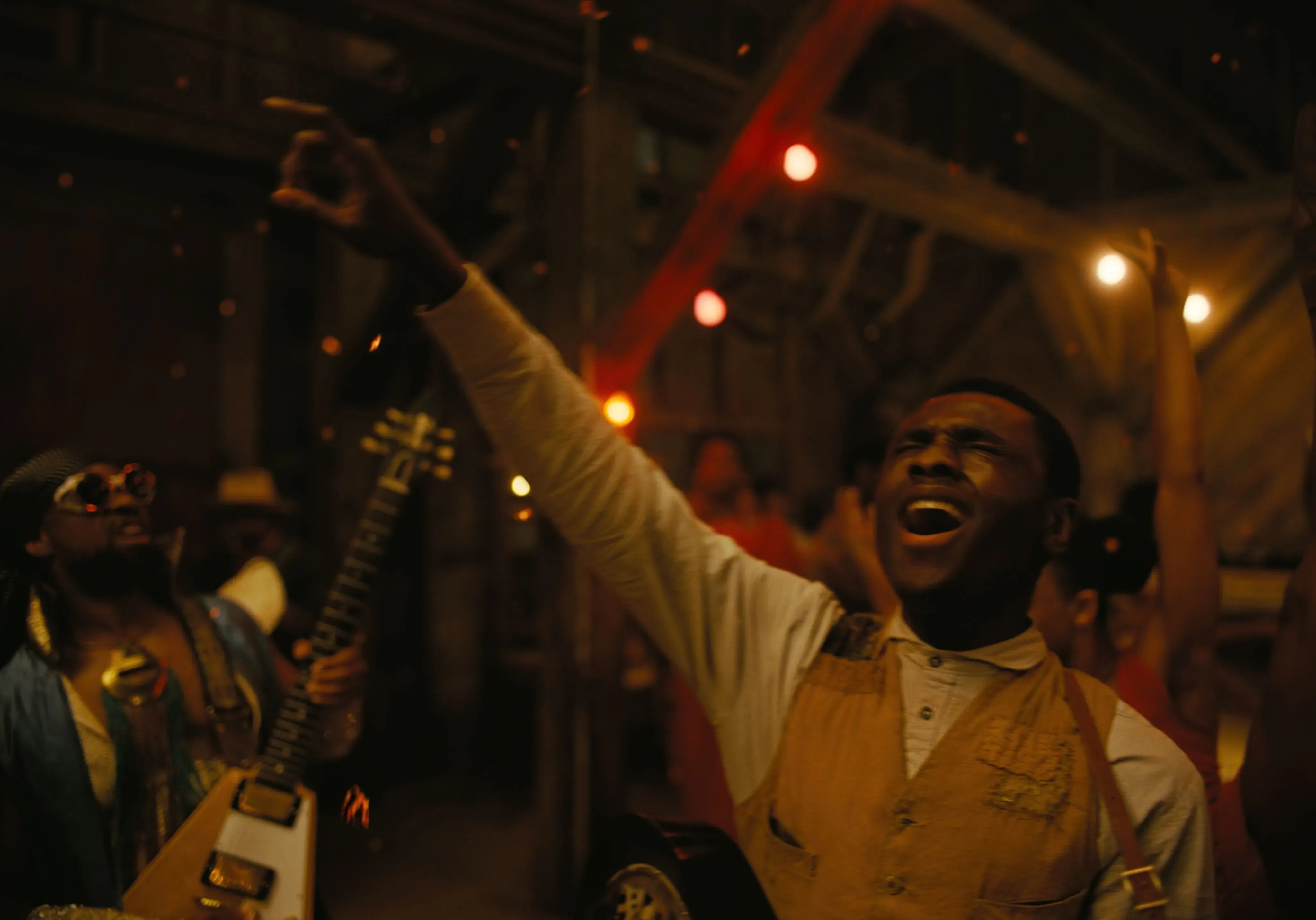 شخصية شابة تغني بحماس في مشهد موسيقي من فيلم "المذنبون"، محاطًا بجو احتفالي يبرز الثقافة الموسيقية والتاريخ العائلي.