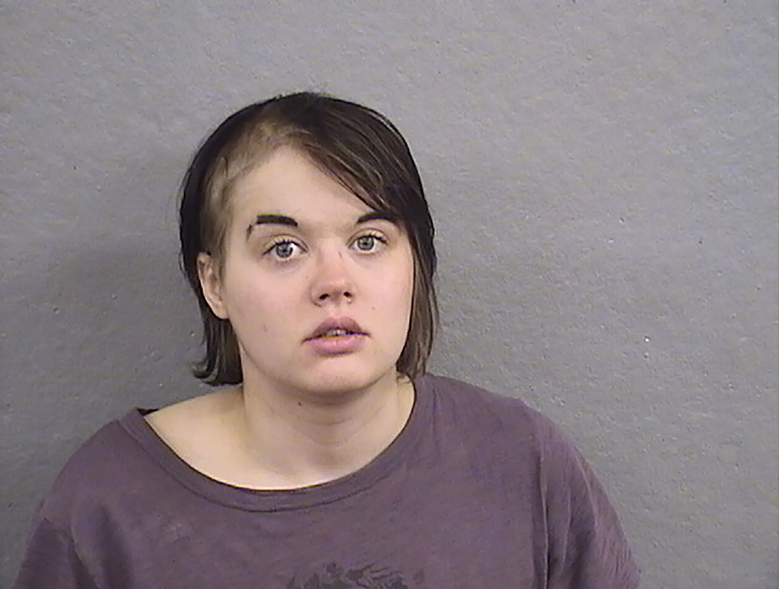 امرأة شابة تبدو في حالة قلق، مع شعر قصير ومظهر شاحب، تظهر في صورة رسمية بعد اعتقالها في ويسكونسن.