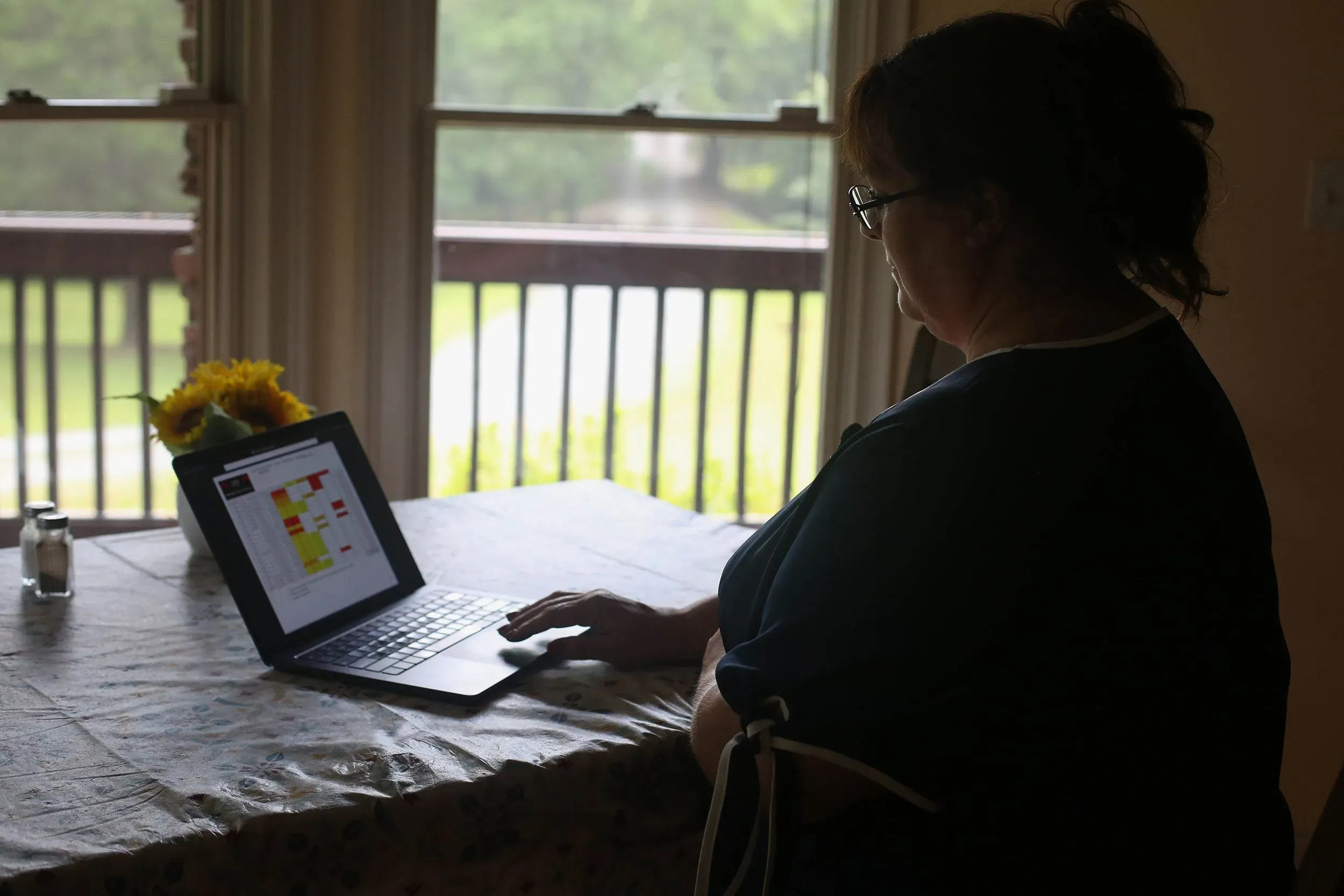 امرأة تجلس على طاولة، تركز على جهاز لوحي يعرض معلومات تتعلق بأعمالها، تعكس تحديات المقاولين مع شركة تسلا.