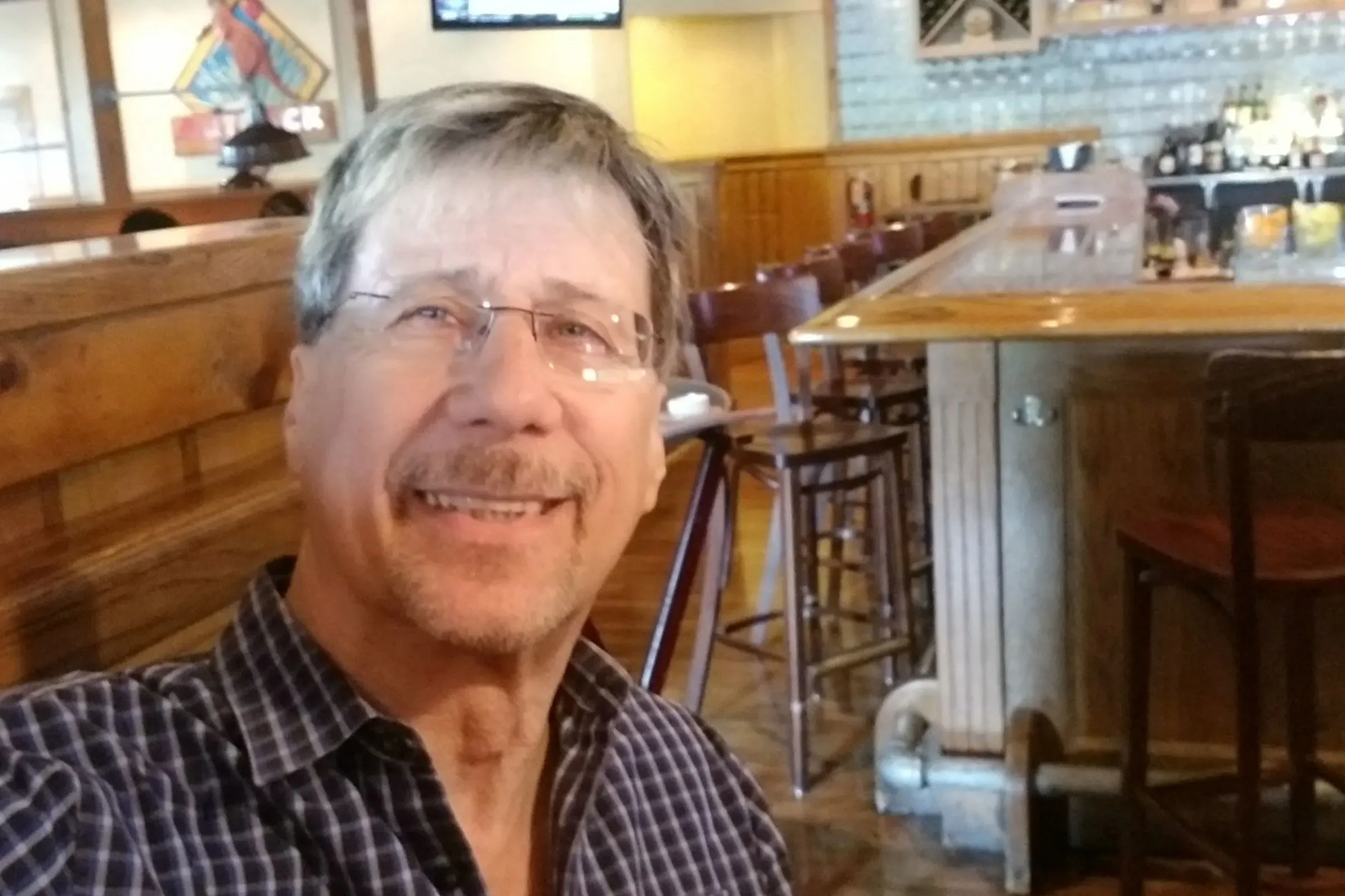 صورة لرجل مسن مبتسم يجلس في مطعم، يعبر عن تحديات الحياة اليومية كمتلقي للضمان الاجتماعي.