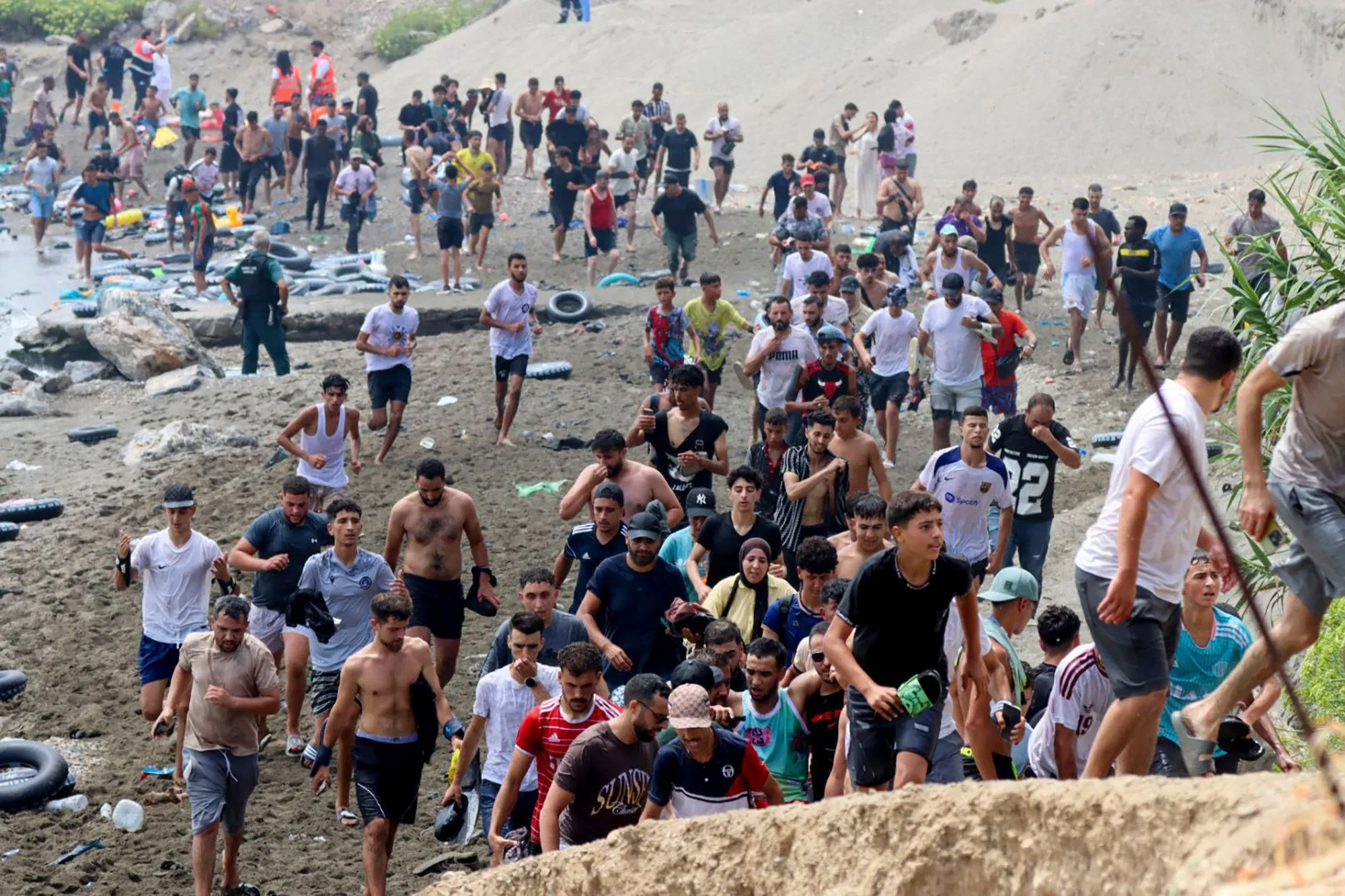 مهاجرون يعبرون شاطئ سبتة في محاولة دخول إسبانيا خلال موجة اقتحام جماعي غير مسبوقة من المغرب، وسط أزمة هجرة كبيرة.