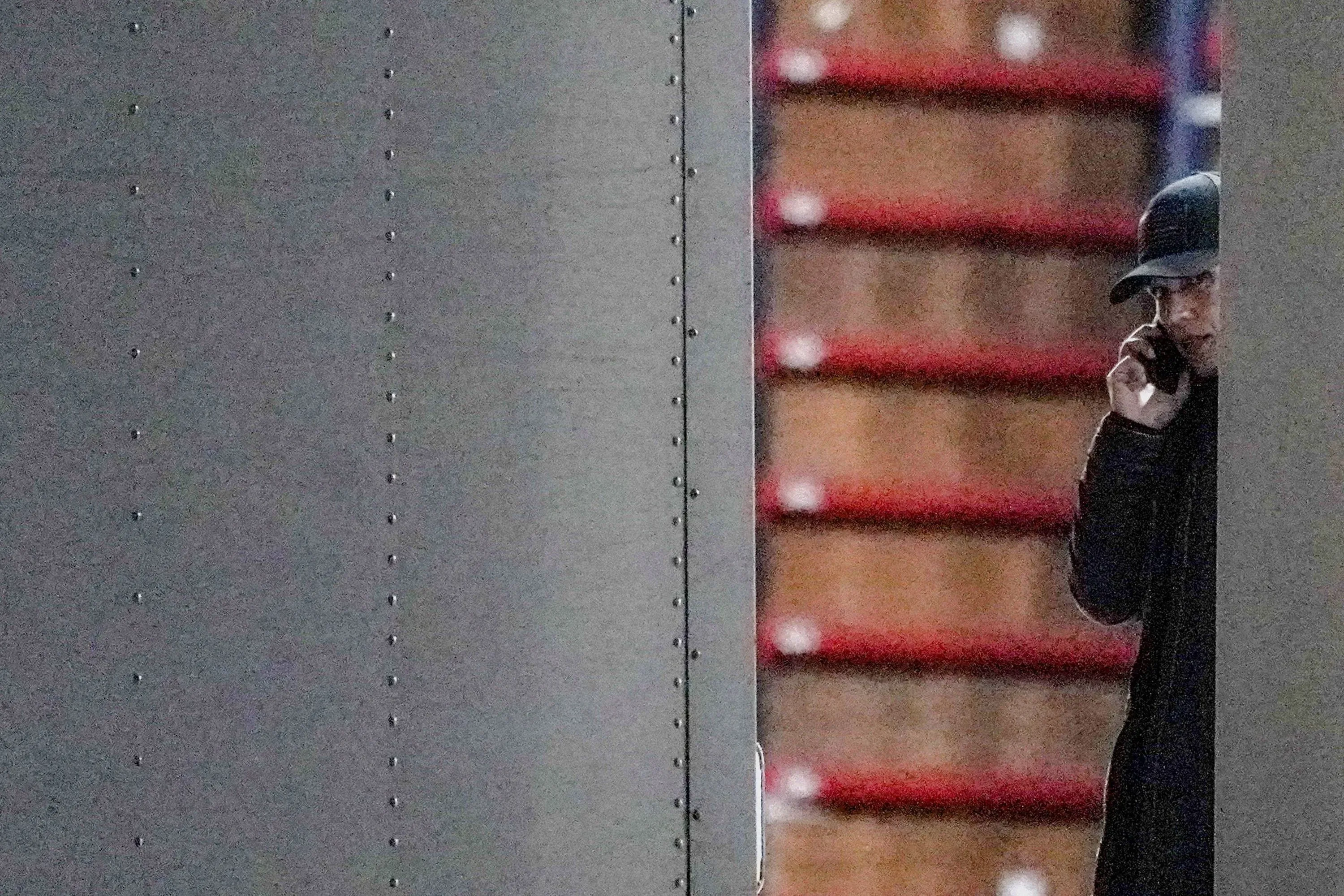 شخص يتحدث عبر الهاتف بالقرب من شاحنة، مع خلفية تحتوي على صناديق، تعكس أجواء الانتخابات والتنسيق الأمني.