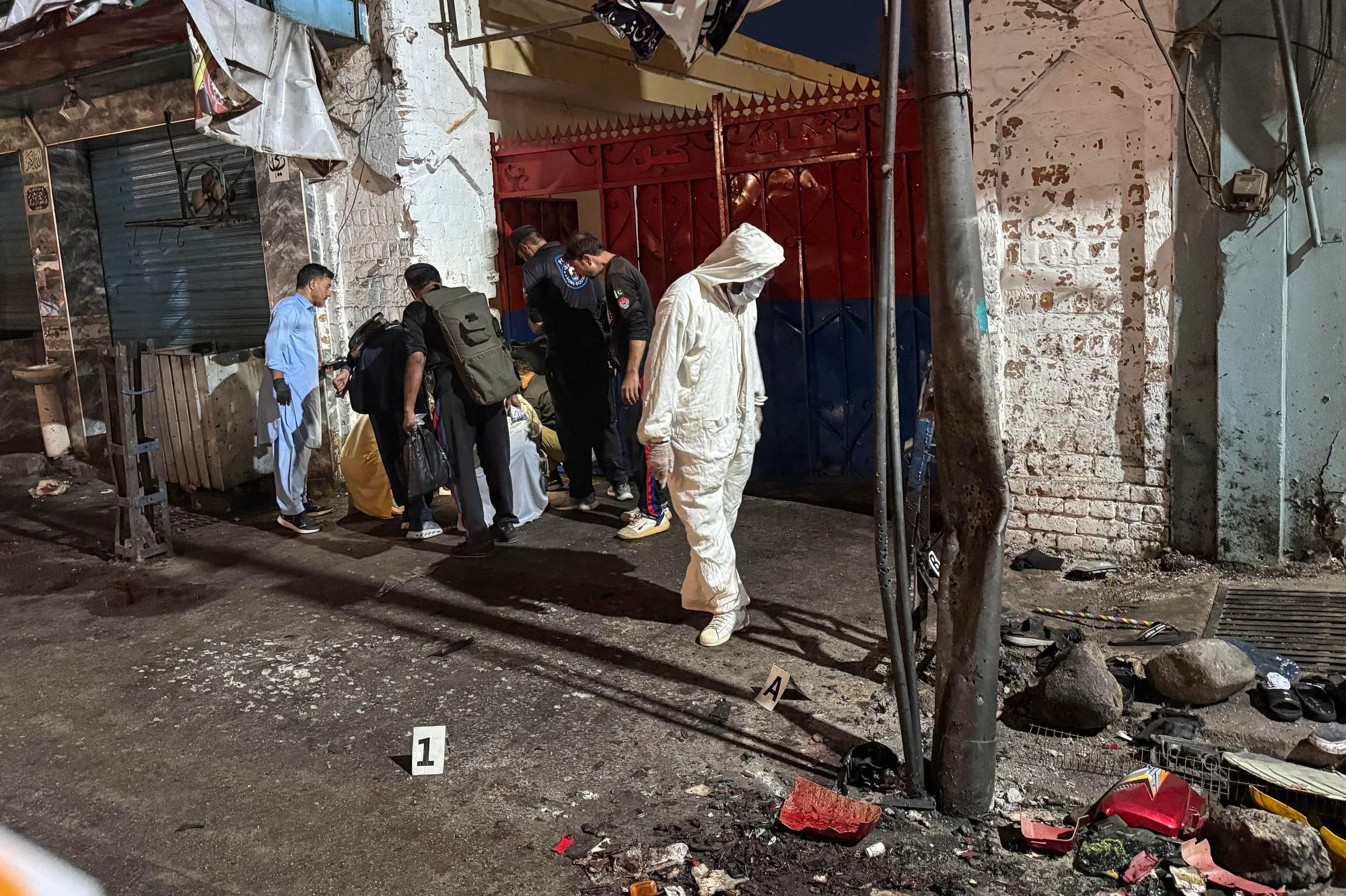 فرق التحقيق الجنائية في موقع تفجير انتحاري استهدف مسيرة مناهضة للمسلحين في وادي سوات شمال غرب باكستان، مع وجود آثار دماء وحطام في الشارع.