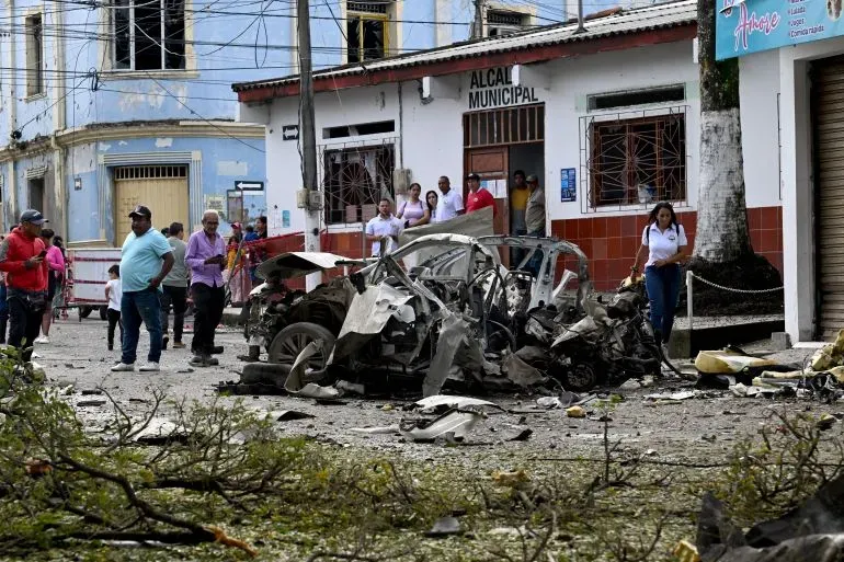 موقع حادث إطلاق النار على السيناتور الكولومبي ميغيل أوريبي، يظهر سيارة مدمرة ومجموعة من الناس يتجمعون في المنطقة.