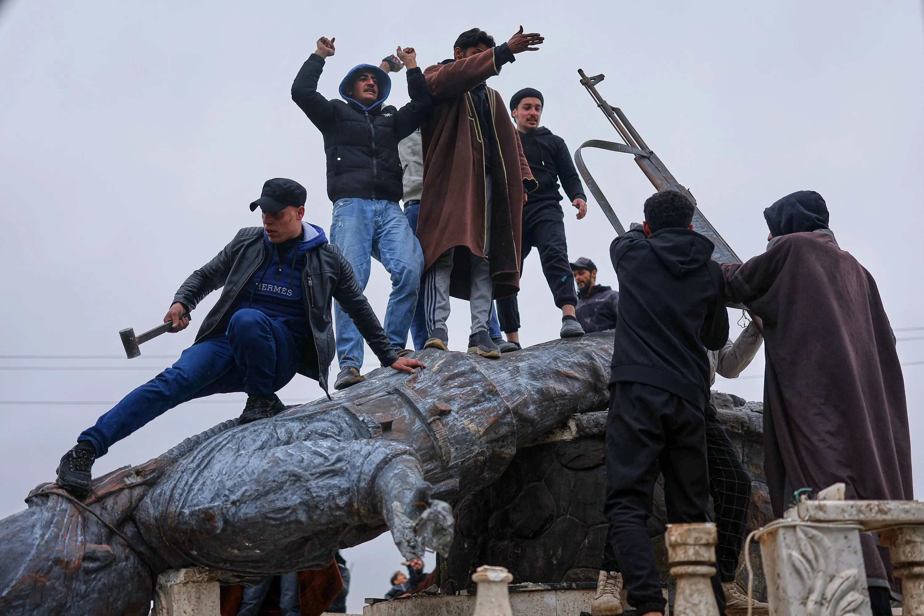 شباب يقومون بإسقاط تمثال في الرقة، مما يعكس التوترات السياسية في شمال سوريا بعد استعادة الجيش السوري للمدينة.