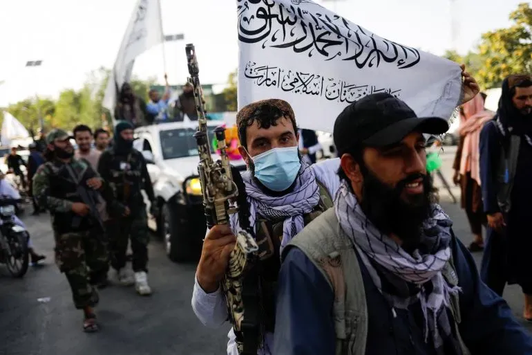 مسلحون من طالبان يحملون علم الحركة في تجمع، وسط توترات على الحدود الطاجيكية الأفغانية بعد هجمات مسلحة.