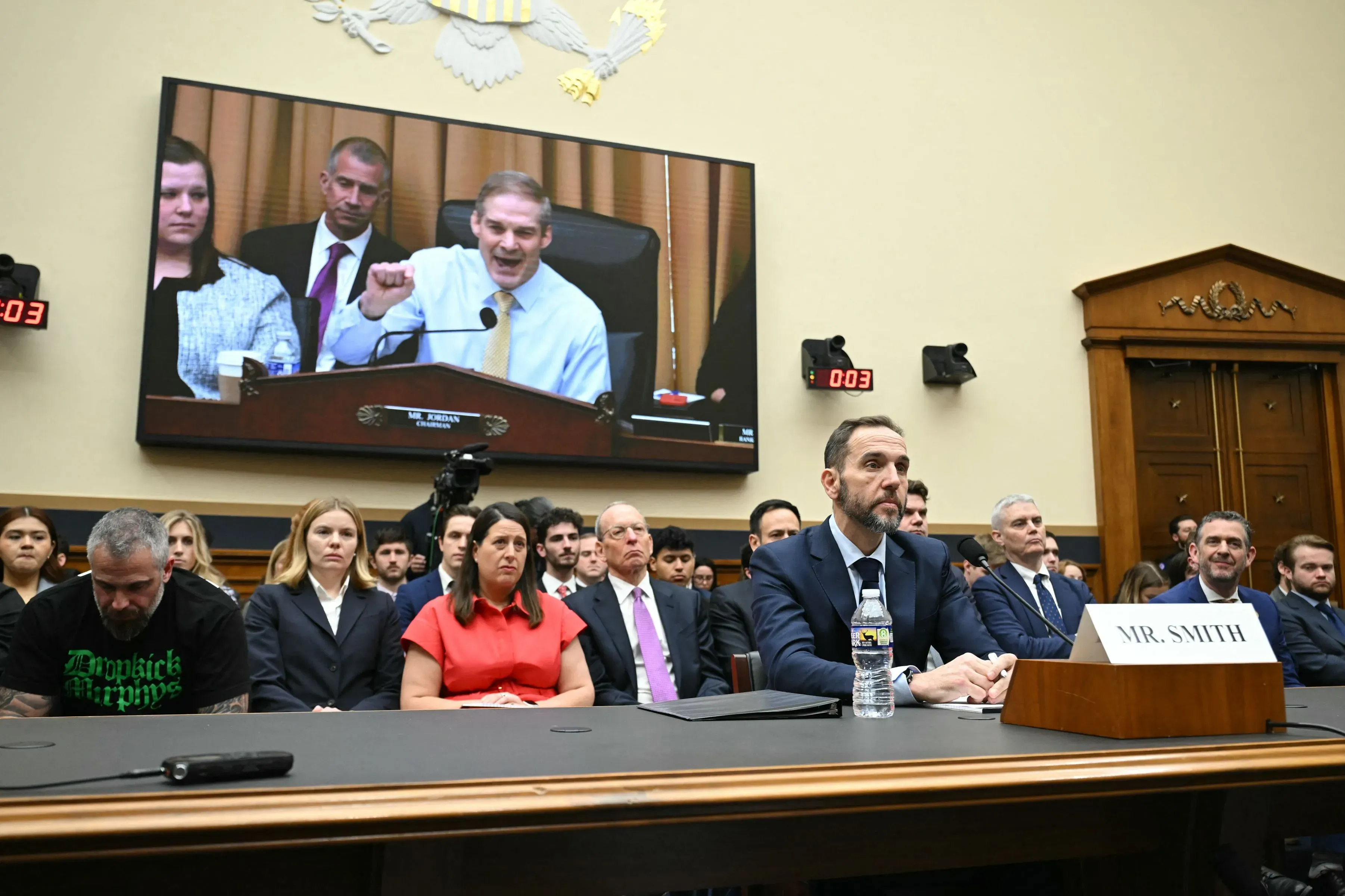 جلسة استماع في الكونغرس حيث يدلي جاك سميث بشهادته، بينما يتحدث النائب جيم جوردان. الحضور يتابعون النقاش حول تحقيقات ترامب.