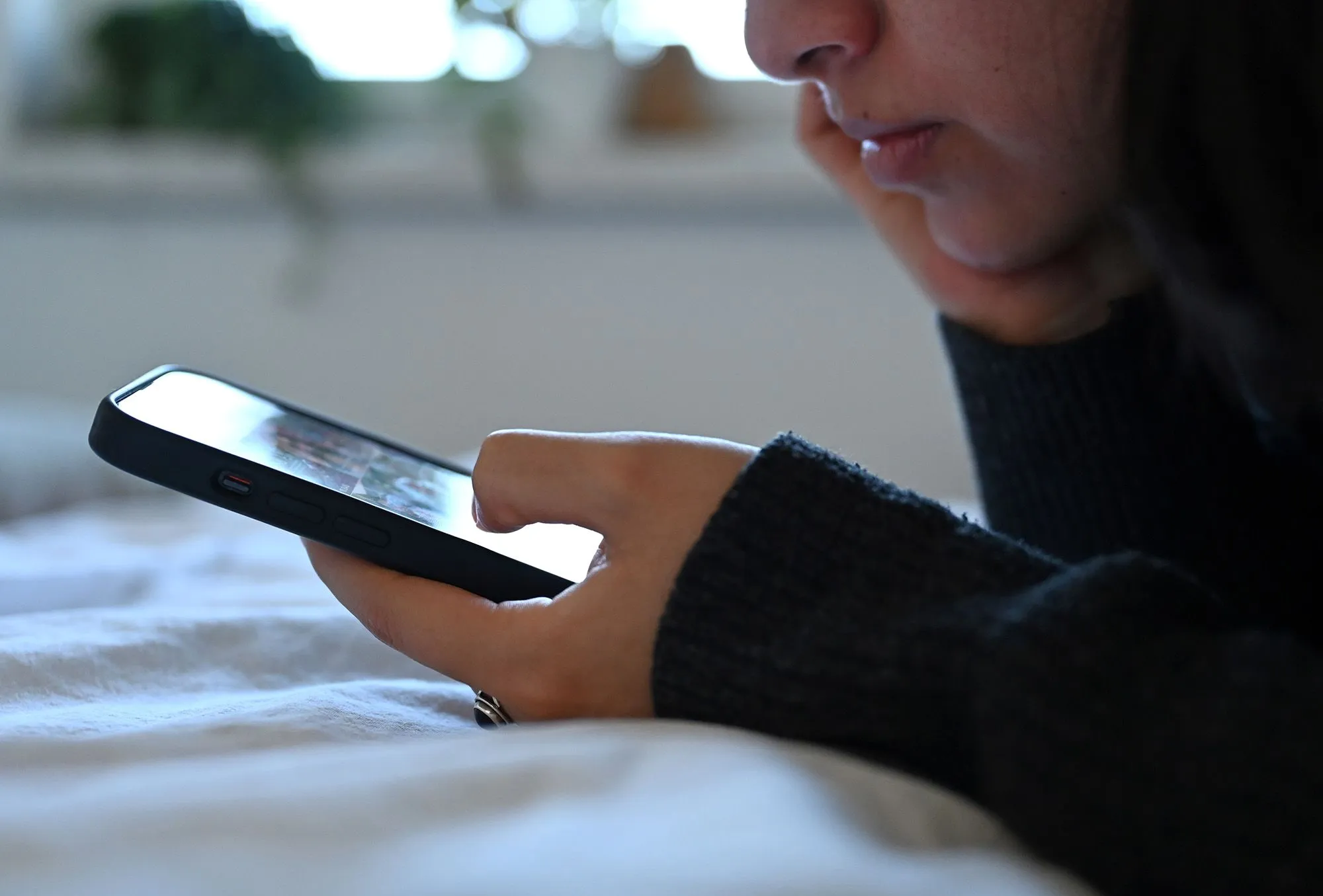 امرأة تتابع محتوى على هاتف ذكي بتركيز، تعبير عن تجربة تخصيص الخلاصات في منصات التواصل الاجتماعي مثل Instagram وTikTok.