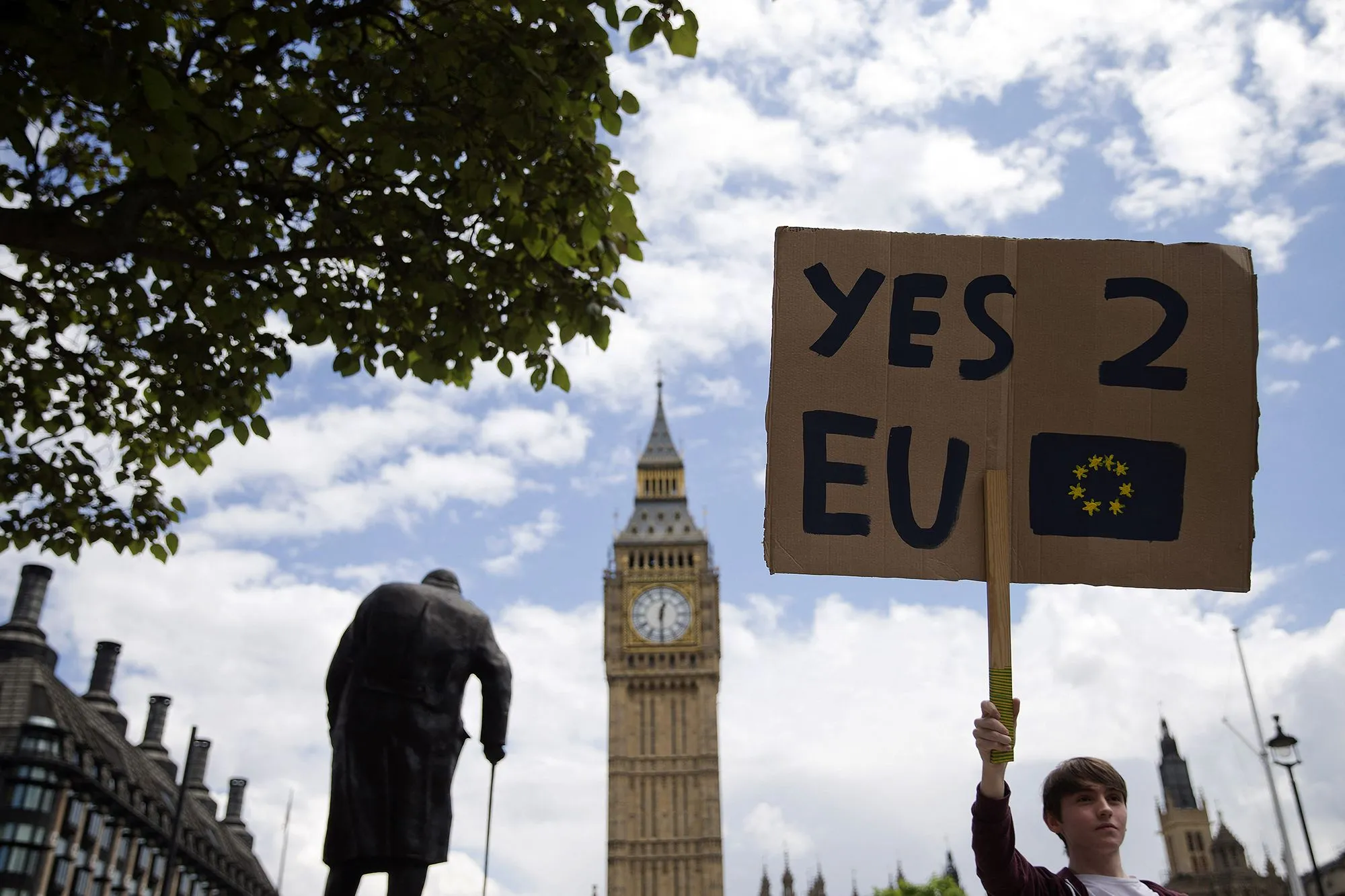 شخص يحمل لافتة مكتوب عليها "نعم 2 EU" أمام ساعة بيغ بن، تعبيراً عن دعم البقاء في الاتحاد الأوروبي وسط أجواء احتجاجية.