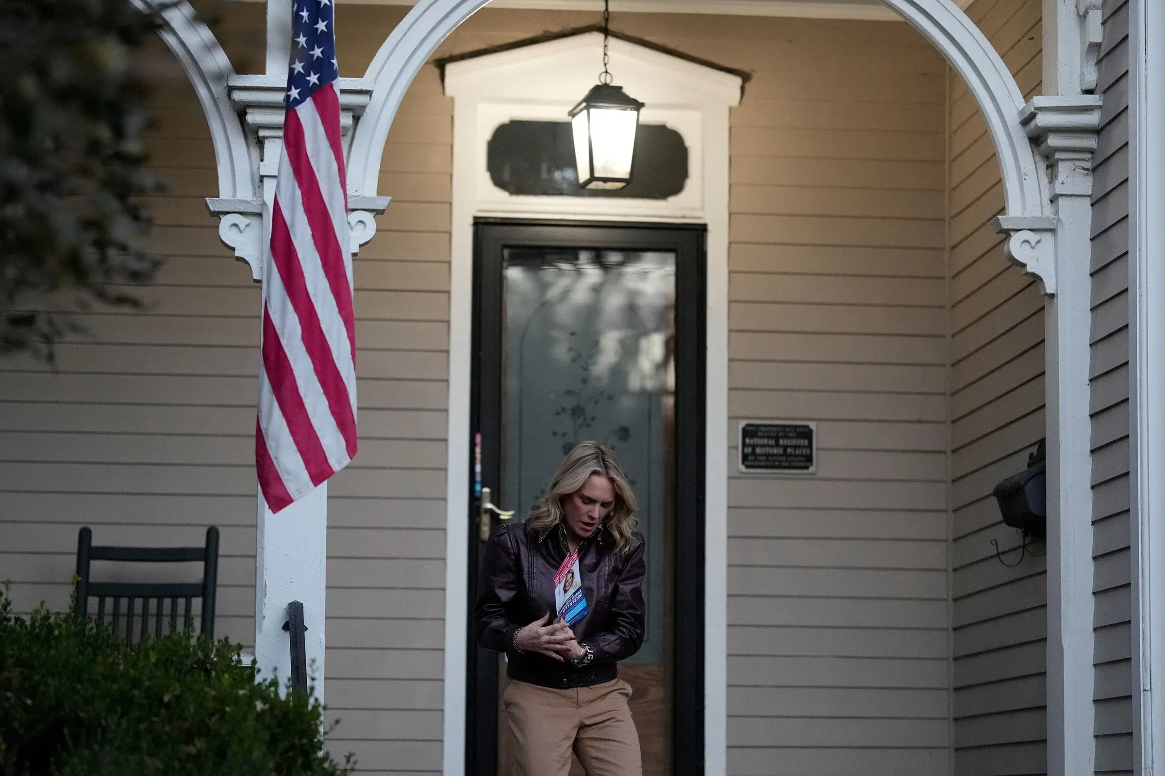 امرأة تحمل منشورات انتخابية أمام منزلها، مع علم أمريكي معلق، تشير إلى نشاط الحملة الانتخابية في تينيسي.