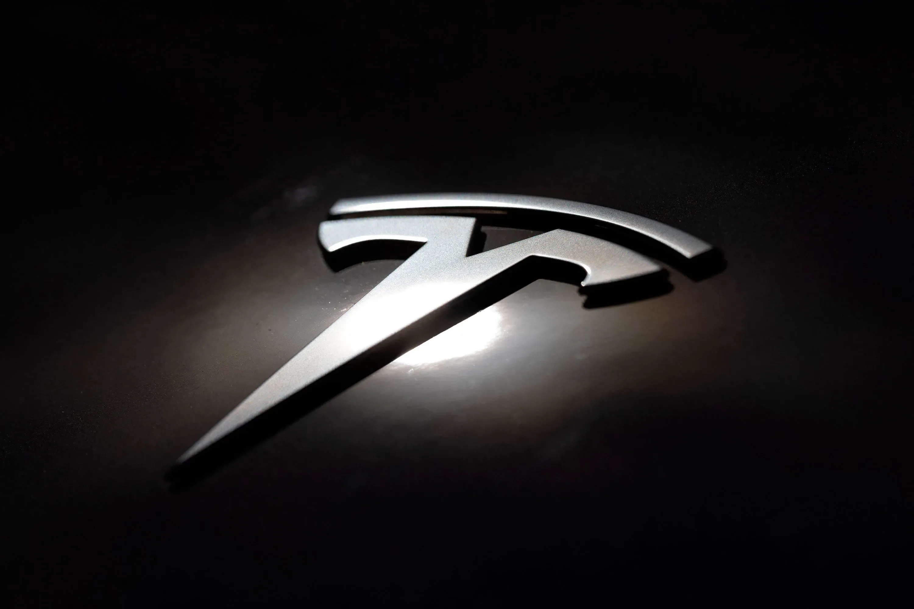 شعار شركة تسلا يظهر بتفاصيل دقيقة على خلفية داكنة، مما يعكس الابتكار في صناعة السيارات الكهربائية.