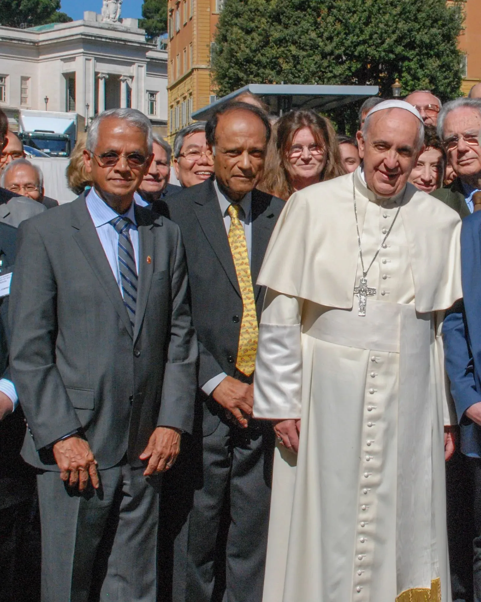 راماناثان يقف مع البابا فرانسيس ومجموعة من العلماء في حدث رسمي، مع خلفية معمارية مميزة، مما يعكس أهمية التعاون في مواجهة التغير المناخي.