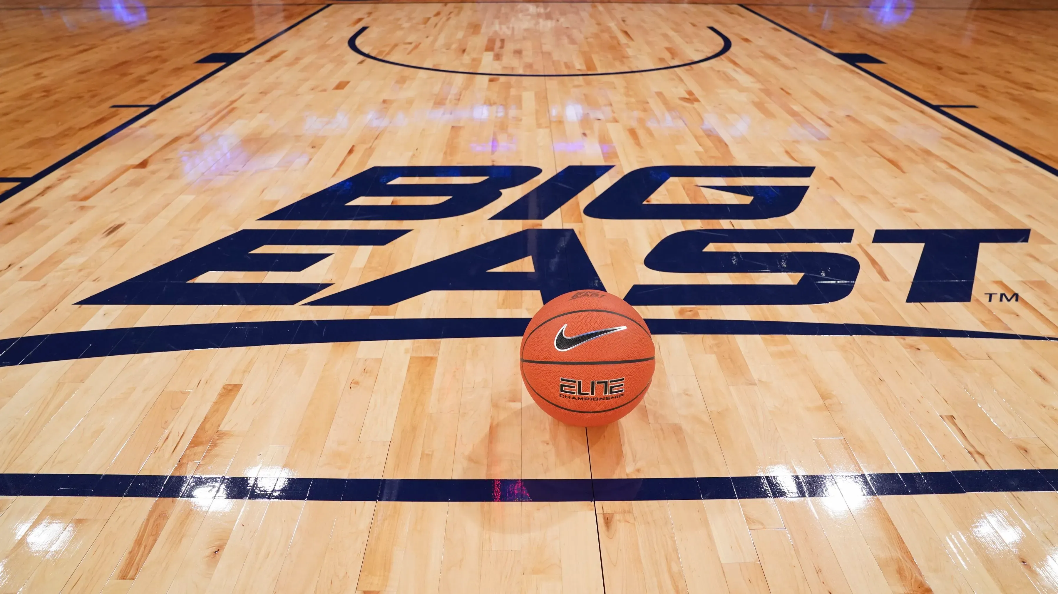 كرة سلة برتقالية على أرضية ملعب تحمل شعار "بيج إيست"، تشير إلى أهمية البطولة في تاريخ كرة السلة الجامعية.