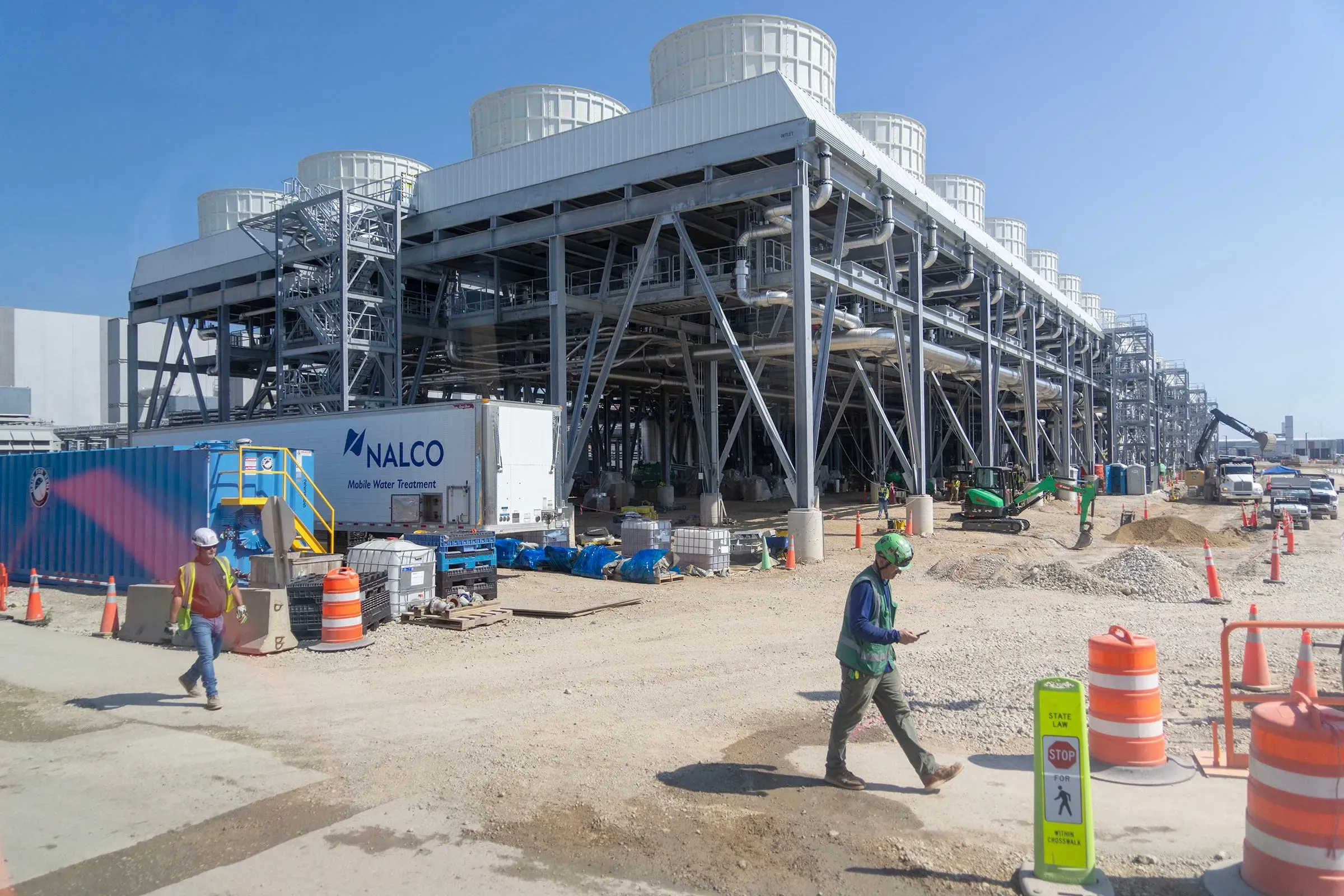 مرافق ضخمة لمعالجة المياه في موقع إنشاء، مع عمال ومعدات، تعكس الاستثمارات الكبيرة في البنية التحتية للذكاء الاصطناعي.