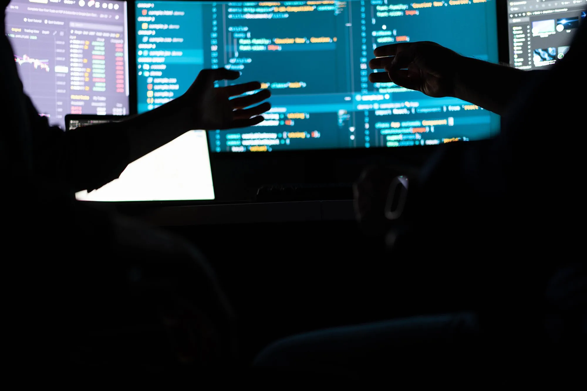 شخصان يناقشان شيفرة برمجية على شاشة كمبيوتر في بيئة مظلمة، تعبير عن استغلال ثغرات أمنية في لغة PHP باستخدام الذكاء الاصطناعي.