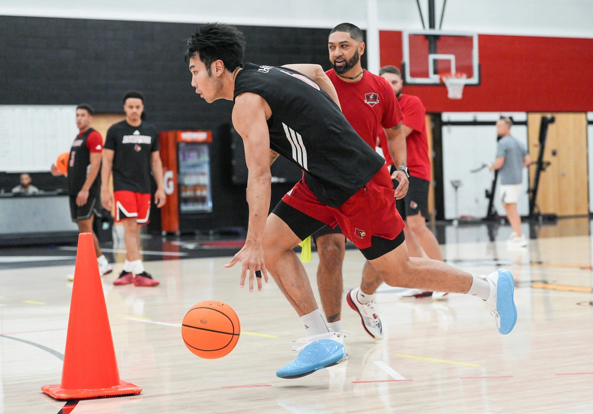 لاعب كرة السلة الصيني Zhang Boyuan يتدرب بحماس في صالة Louisville Cardinals استعدادًا لمباريات NCAA تحت إشراف المدرب Eli Foy.