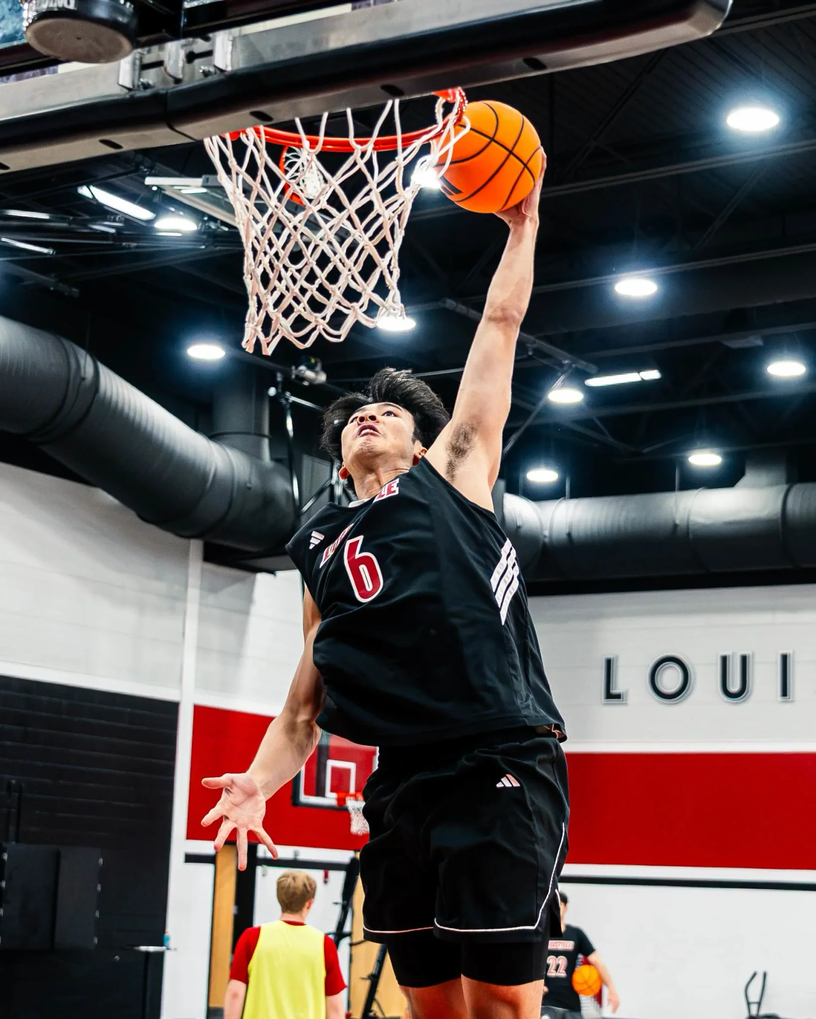 لاعب كرة سلة صيني يرتدي قميص رقم 6 ينفذ تصويبة دانك في تدريب فريق Louisville Cardinals استعداداً لموسم NCAA.
