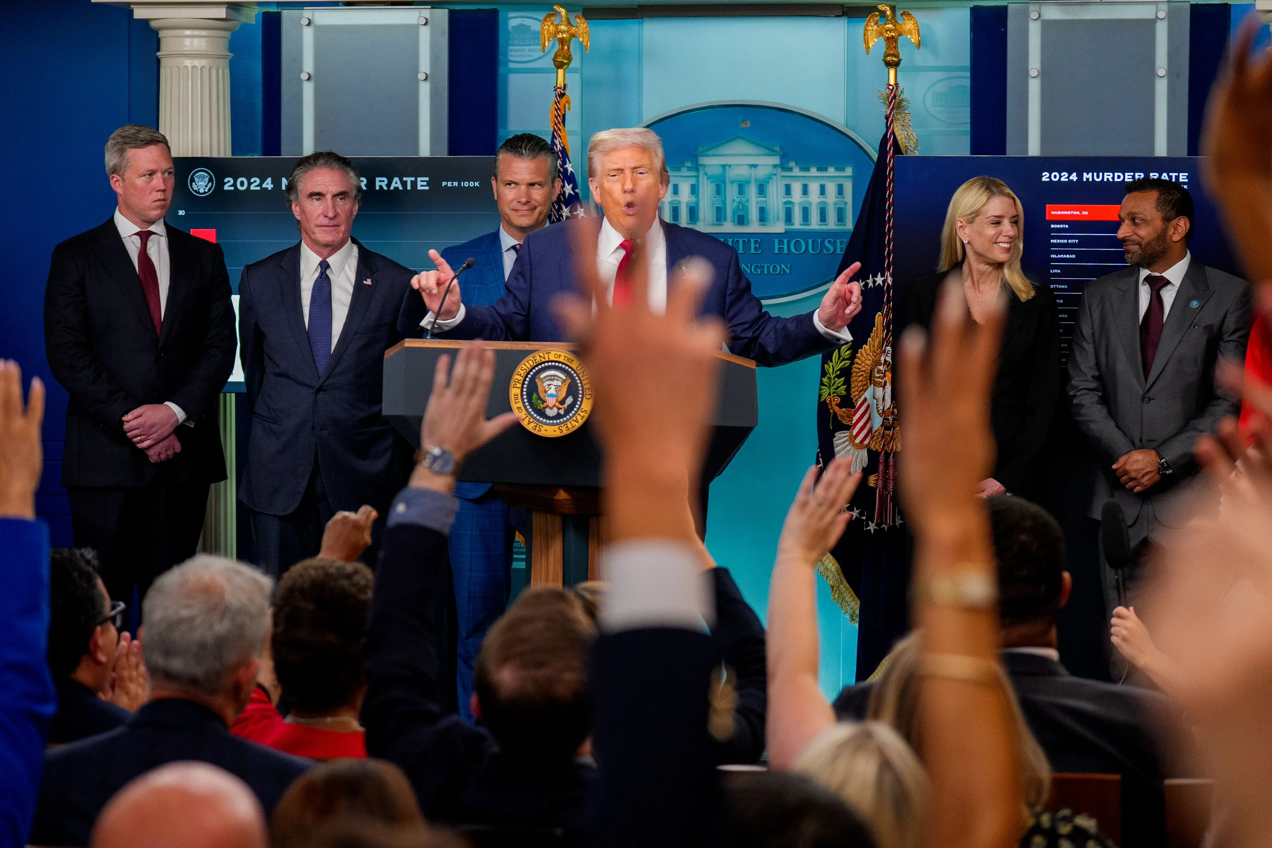 ترامب يتحدث في مؤتمر صحفي بالبيت الأبيض، محاطًا بمساعديه، حيث يناقش قضايا الأمن والعنف في المدن الكبرى.