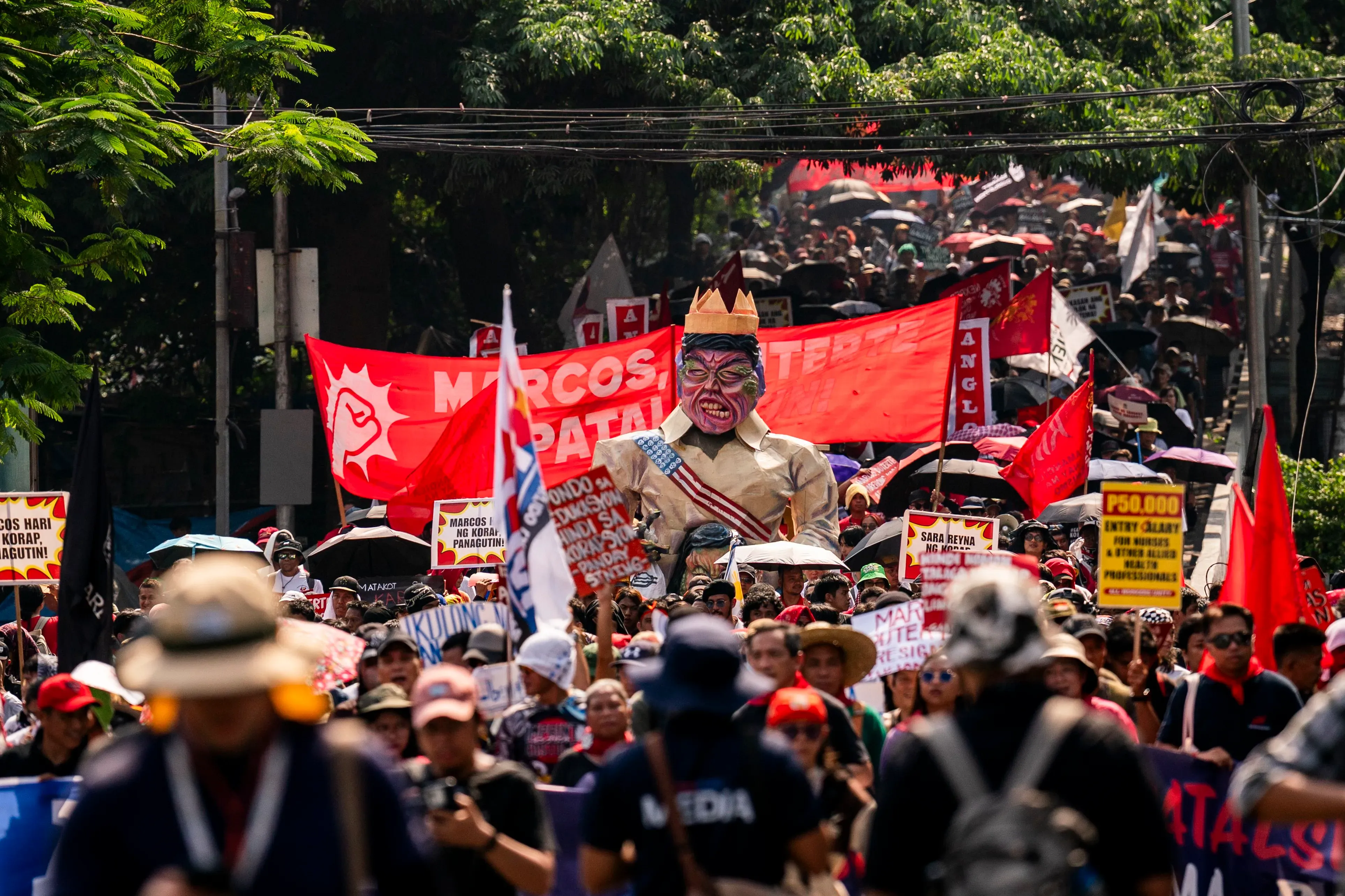 مظاهرة حاشدة في مانيلا ضد الفساد، حيث يحمل المتظاهرون لافتات ويظهر تمثال ضخم لشخصية سياسية، تعبيرًا عن الغضب الشعبي.