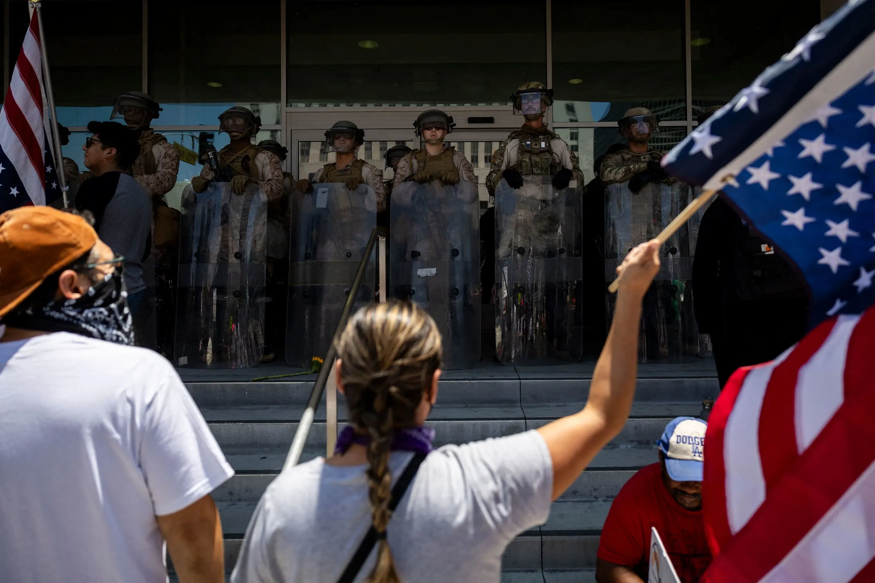 محتجون يحملون لافتات ويرتدون أقنعة، بينما يقف رجال الشرطة في زي عسكري خلف دروعهم، خلال مسيرة "لا للملوك".