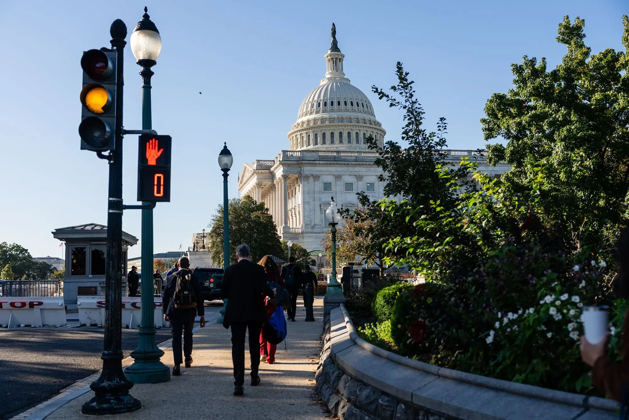 مشهد لشارع بالقرب من مبنى الكابيتول الأمريكي، مع إشارة مرور حمراء تعني "توقف"، ويظهر المارة في الطريق.
