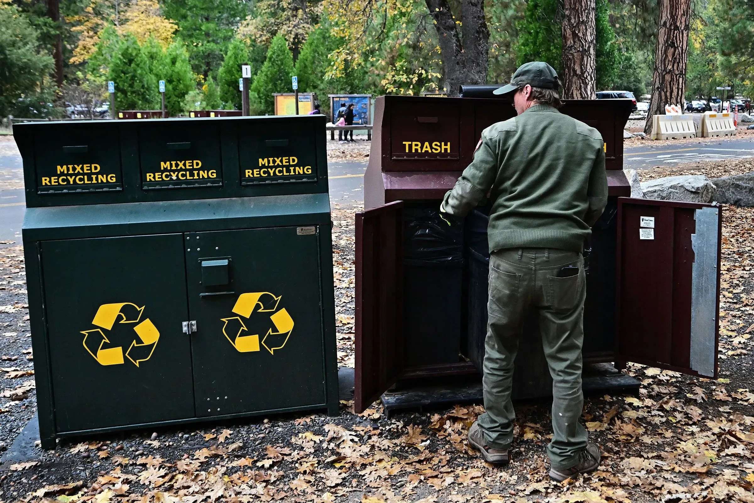 موظف حكومي يقوم بإفراغ النفايات من حاويات إعادة التدوير في حديقة وطنية، مما يعكس جهود الحفاظ على البيئة بعد الإغلاق الحكومي.