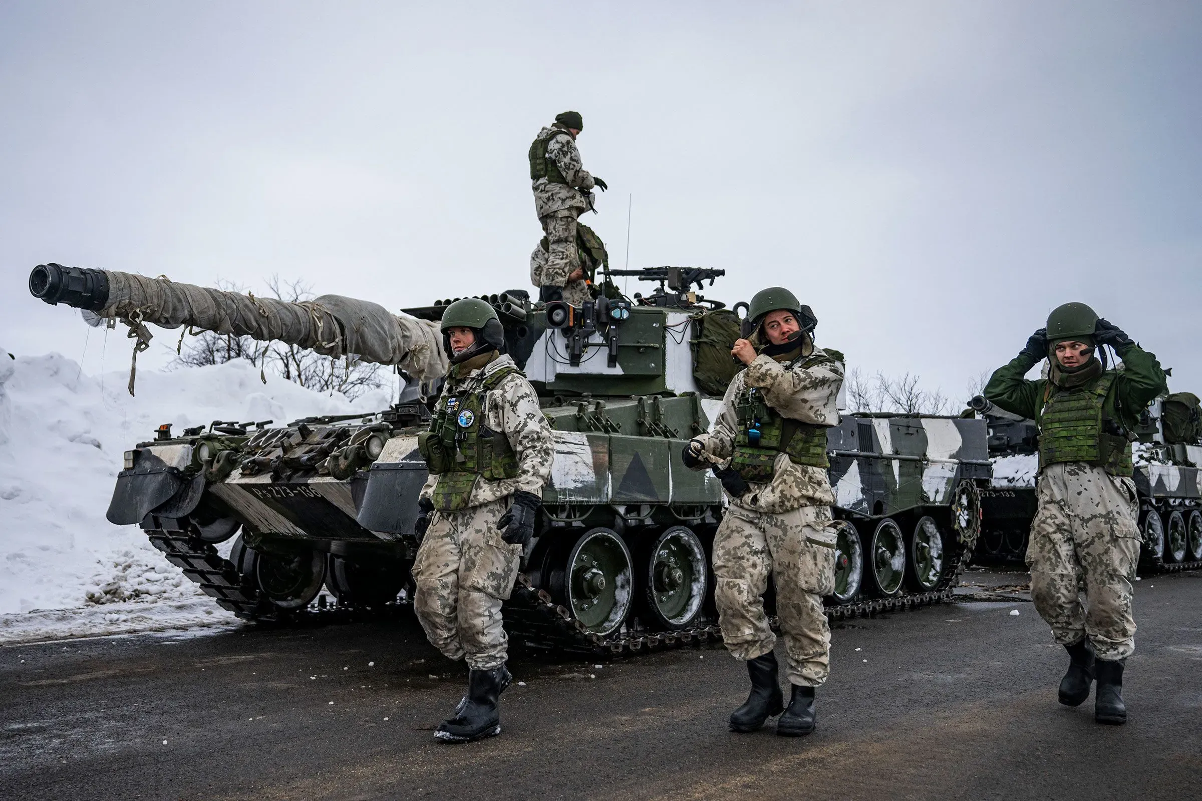 جنود يرتدون زيًا عسكريًا يتواجدون حول دبابة في منطقة ثلجية، مما يعكس التوترات العسكرية المتزايدة في القطب الشمالي.