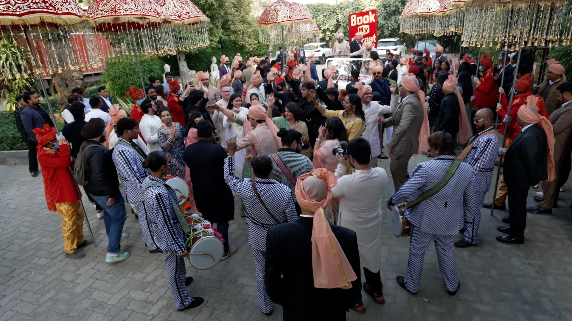 حفل زفاف مزدحم في دلهي، حيث يحتفل الضيوف مع الموسيقى والرقص، محاطين بالزينة الفاخرة والأجواء الاحتفالية.