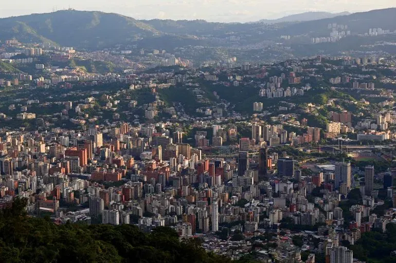 منظر بانورامي لمدينة كاراكاس، يظهر المباني الشاهقة والجبال المحيطة، مع تباين بين الحياة الحضرية والطبيعة.