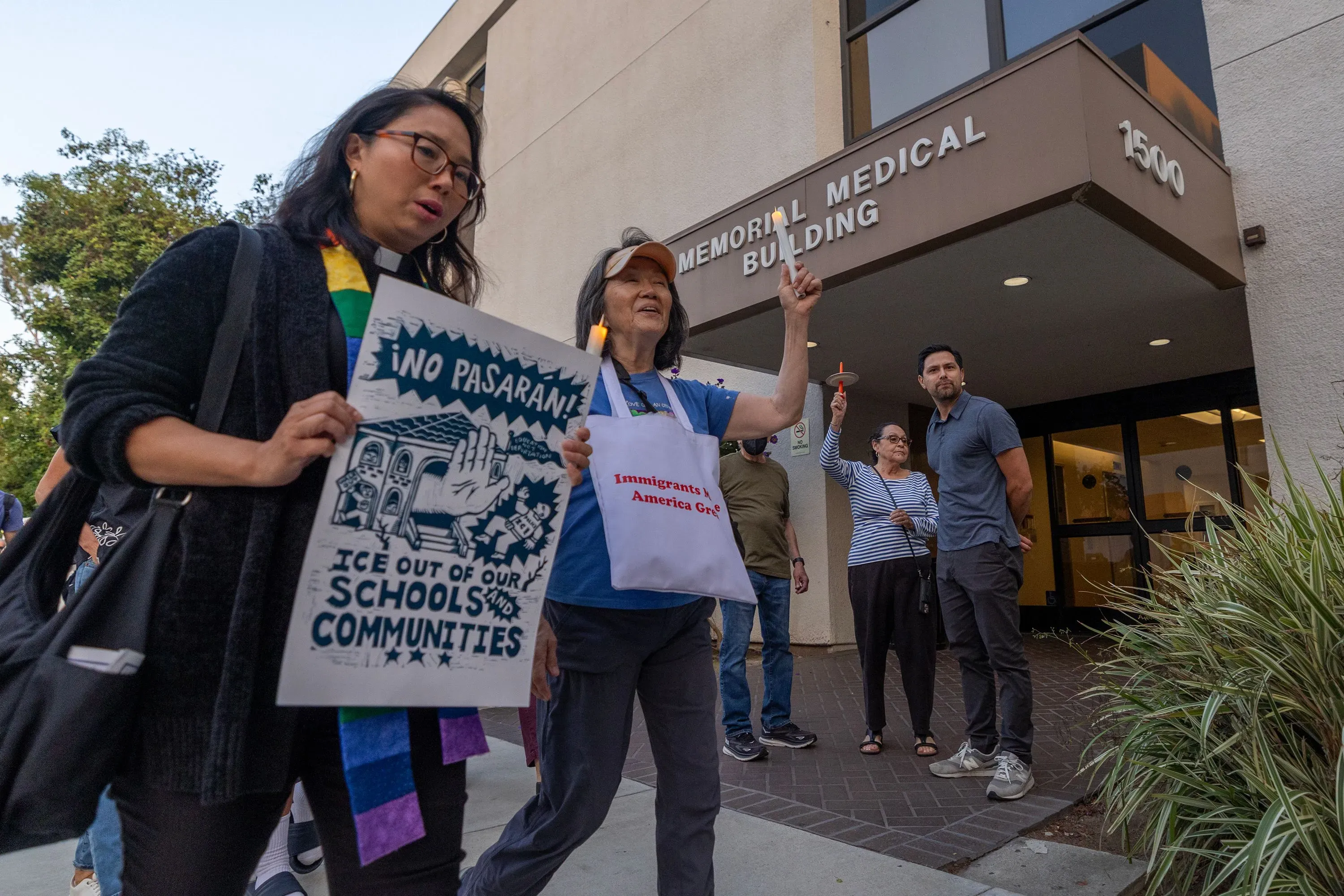 متظاهرون يحملون لافتات أمام مبنى طبي، يعبرون عن رفضهم لوجود عملاء الهجرة في أماكن الرعاية الصحية.