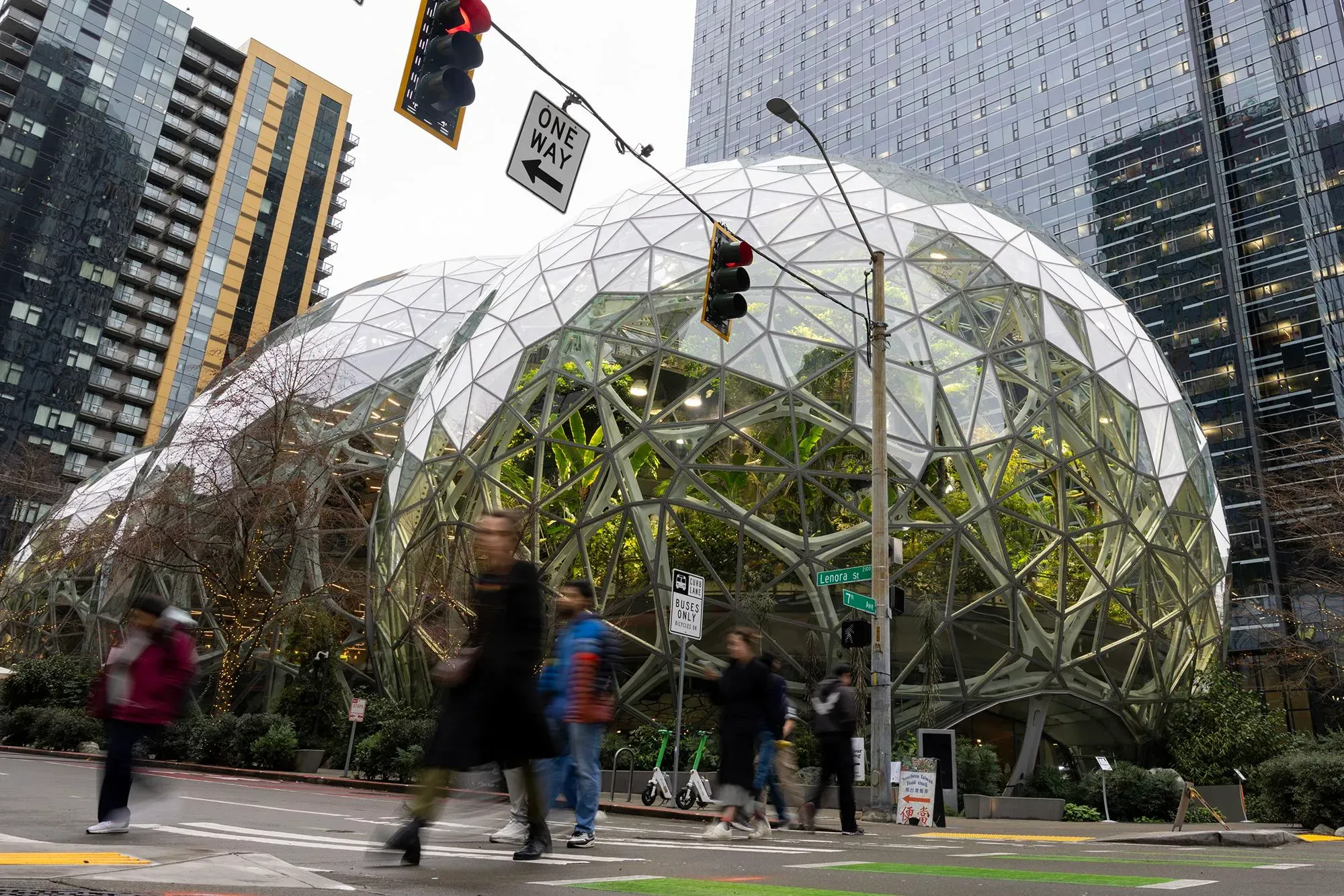 مبنى زجاجي حديث في مدينة مزدحمة، حيث يسير الناس في الشارع. يعكس التصميم المعماري الابتكار في بيئة العمل.