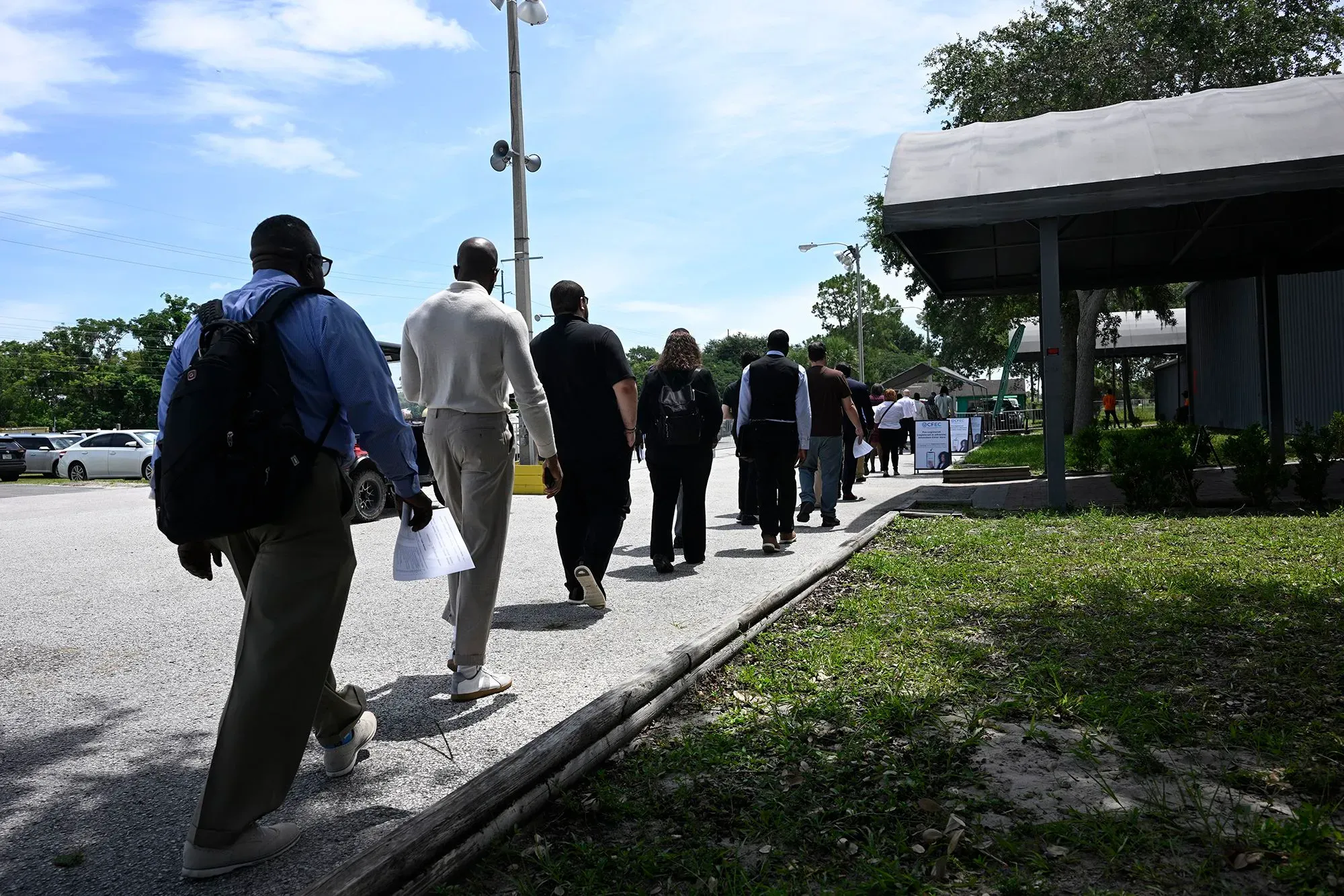 طابور من الأشخاص ينتظرون في موقع التوظيف، يعكس التحديات في سوق العمل الأمريكي وبيانات الوظائف الضعيفة.