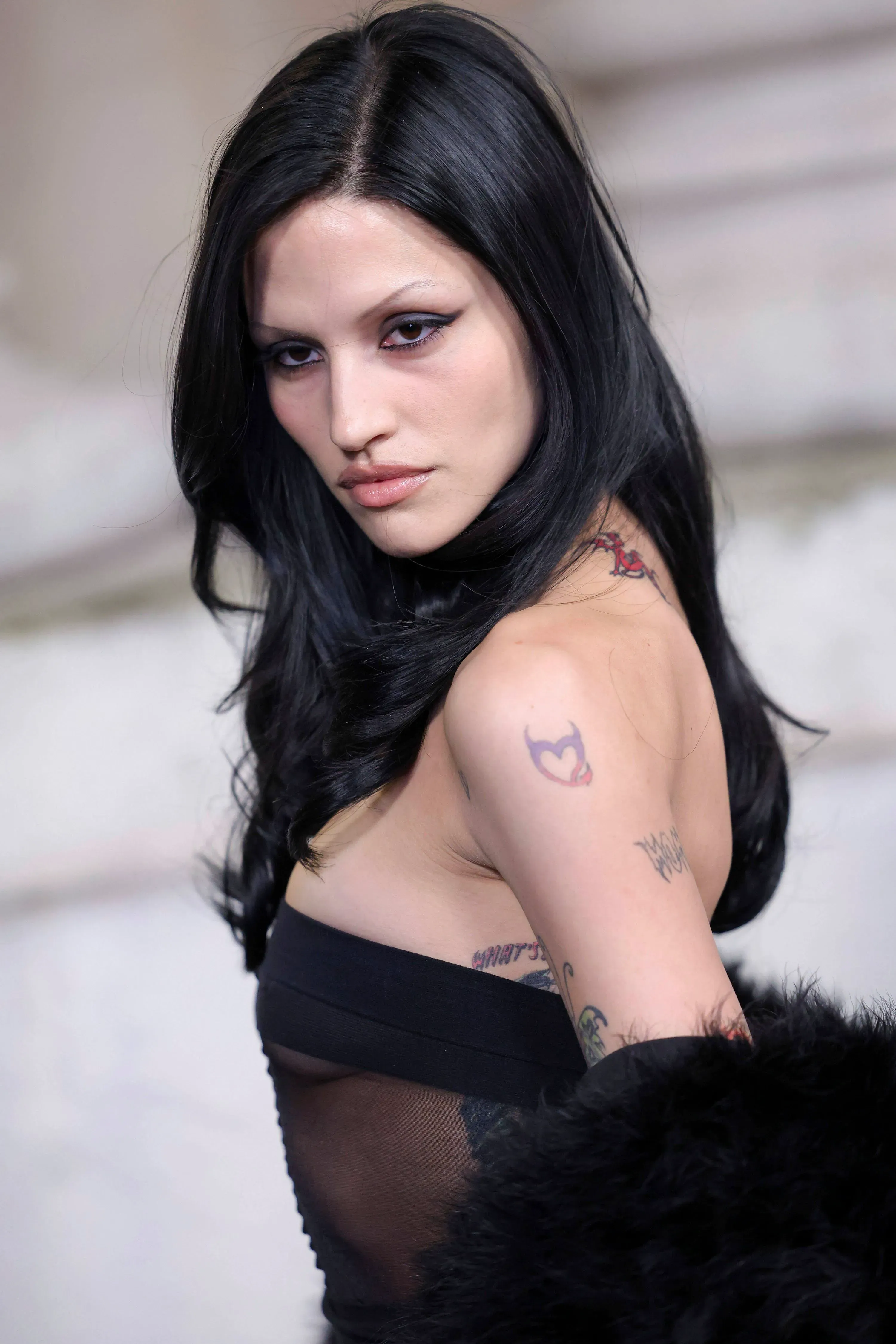 مظهر "الفتاة المتعبة" مع عيون مظللة وشفتين بلون أرجواني، يعكس صيحات الجمال الحديثة ويحتفي بالعيوب.