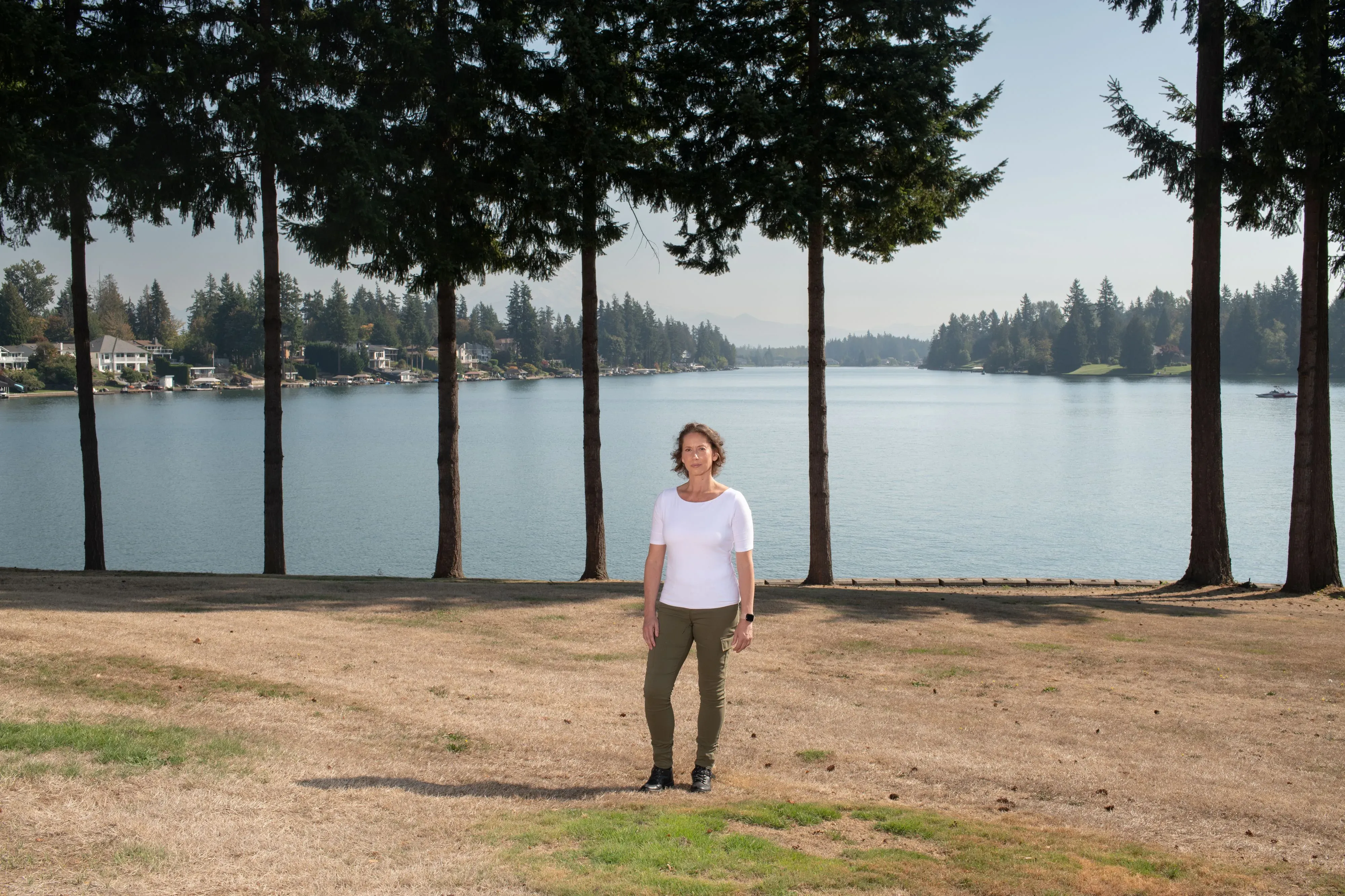 امرأة تقف على ضفة بحيرة هادئة محاطة بأشجار طويلة، تعكس الأجواء السلمية في منطقة بيفرلي هيلز.