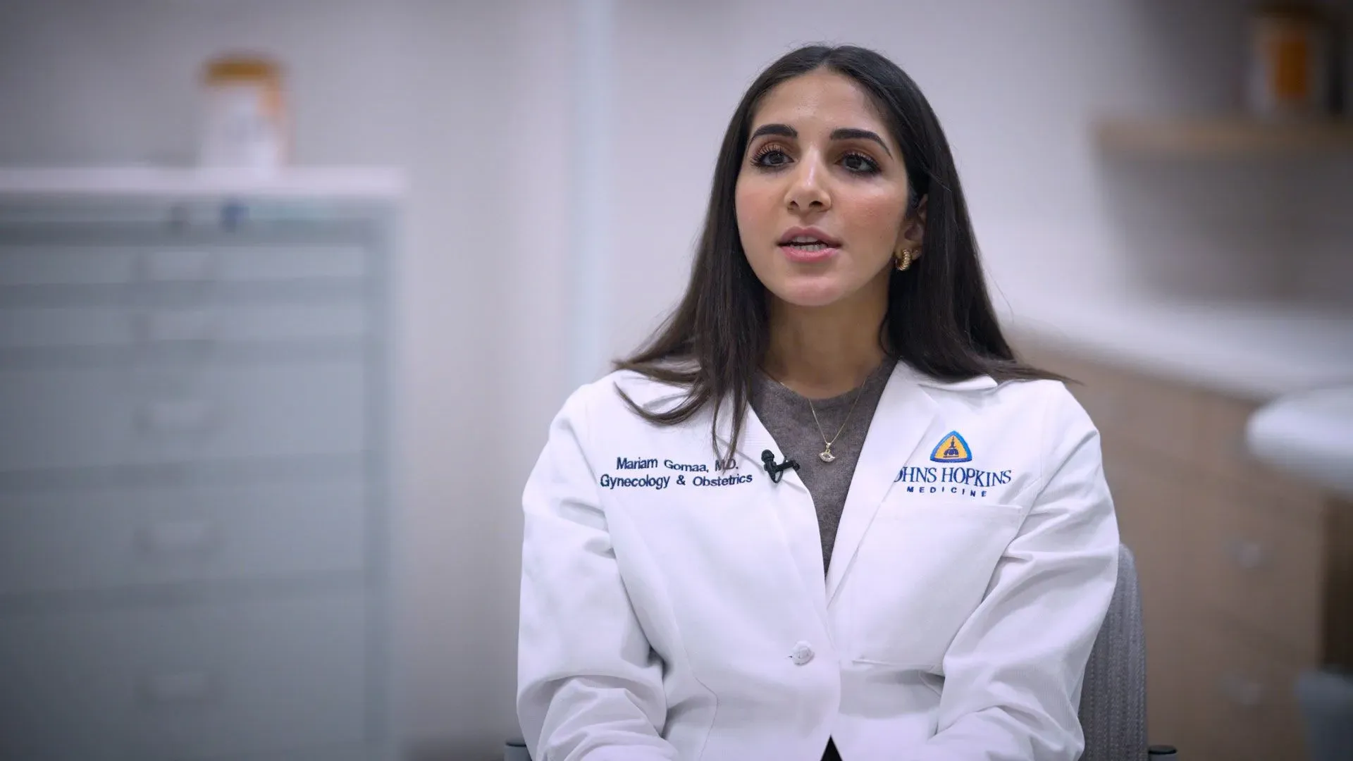 طبيبة نسائية تتحدث في عيادة، ترتدي زيًا طبيًا، تناقش موضوع وسائل منع الحمل وتأثيراتها الصحية.