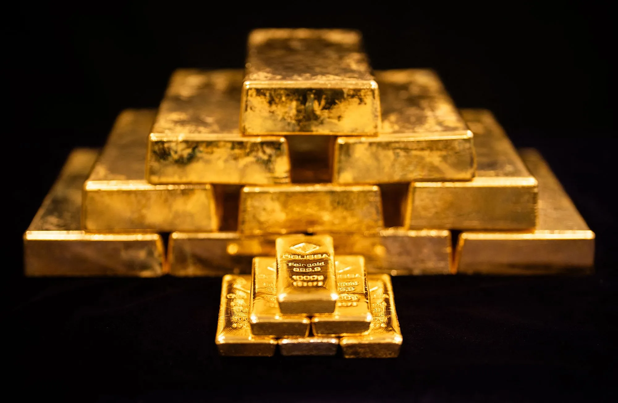 سبائك ذهبية مرتبة في شكل هرمي تمثل قيمة الذهب المستخرج تاريخياً مقارنة بالدين الأمريكي الذي يتجاوز 40 تريليون دولار.