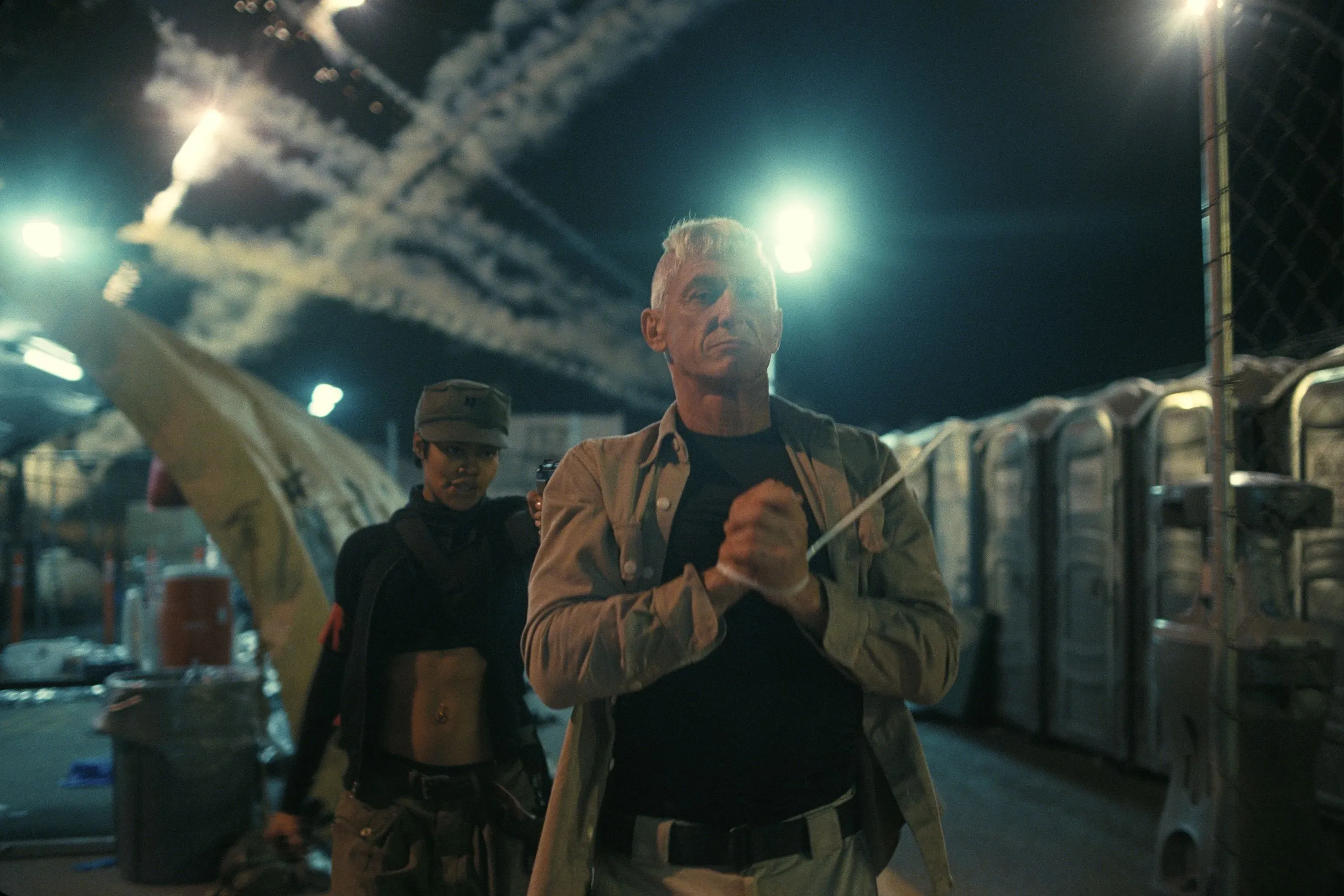 مشهد درامي من فيلم "مارتي سوبريم" يظهر شخصية رئيسية وسط أجواء متوترة، مع إضاءة ساطعة وأجواء عسكرية.