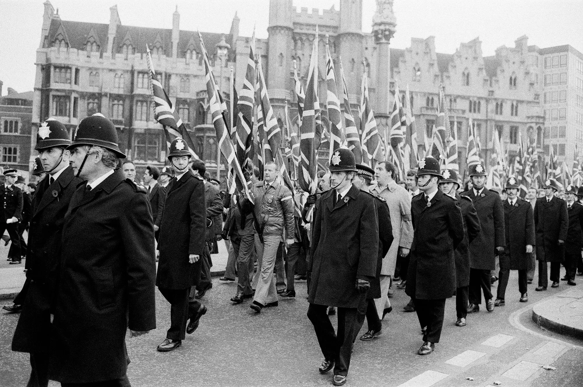 مظاهرة تاريخية في لندن، حيث يسير رجال الشرطة بجانب حشود تحمل أعلام المملكة المتحدة، مما يعكس التوترات الوطنية في البلاد.