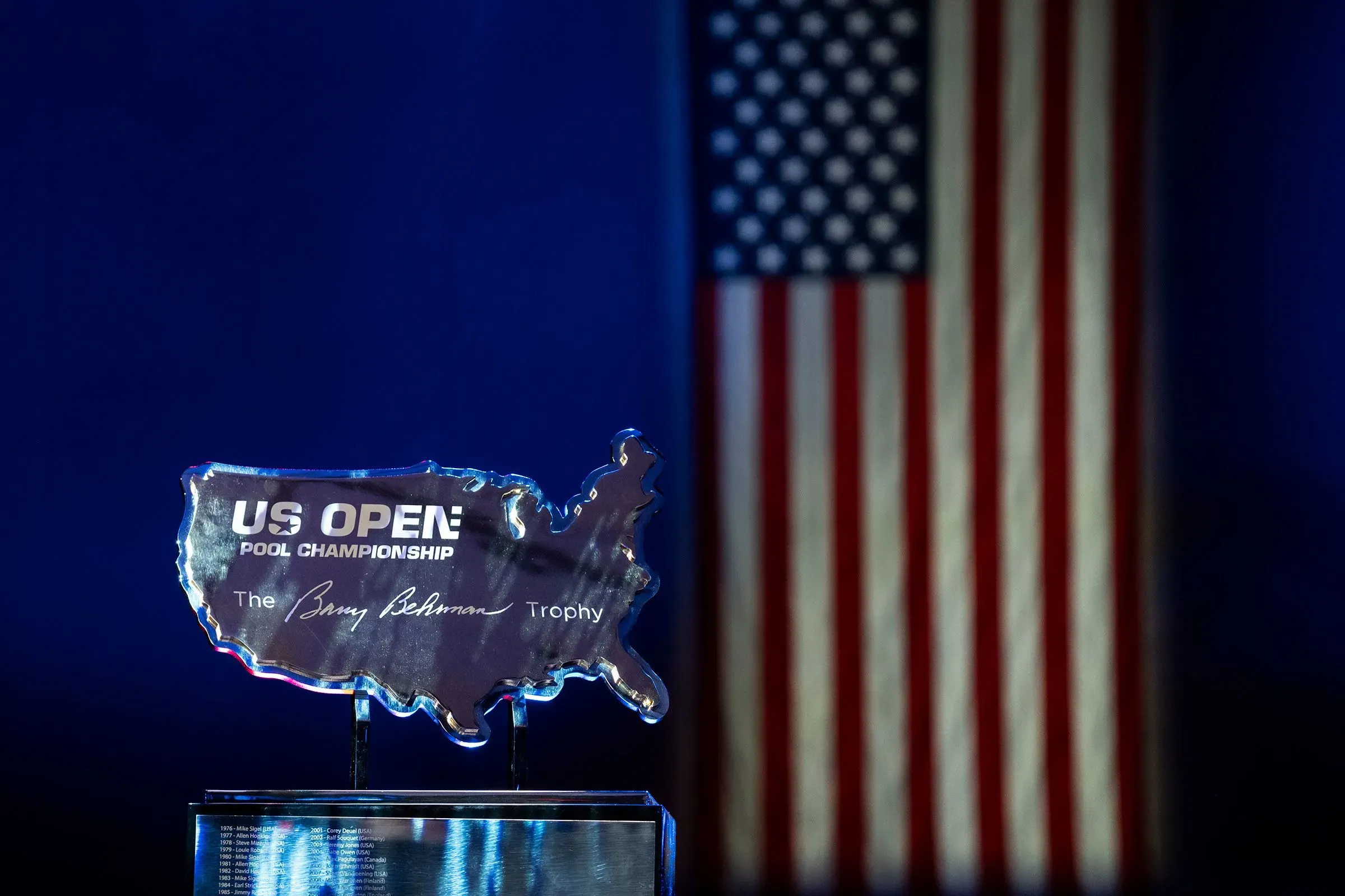 كأس بطولة الولايات المتحدة المفتوحة للبلياردو، بشكل خريطة الولايات المتحدة، مع العلم الأمريكي في الخلفية، يرمز للتنافس الرياضي.