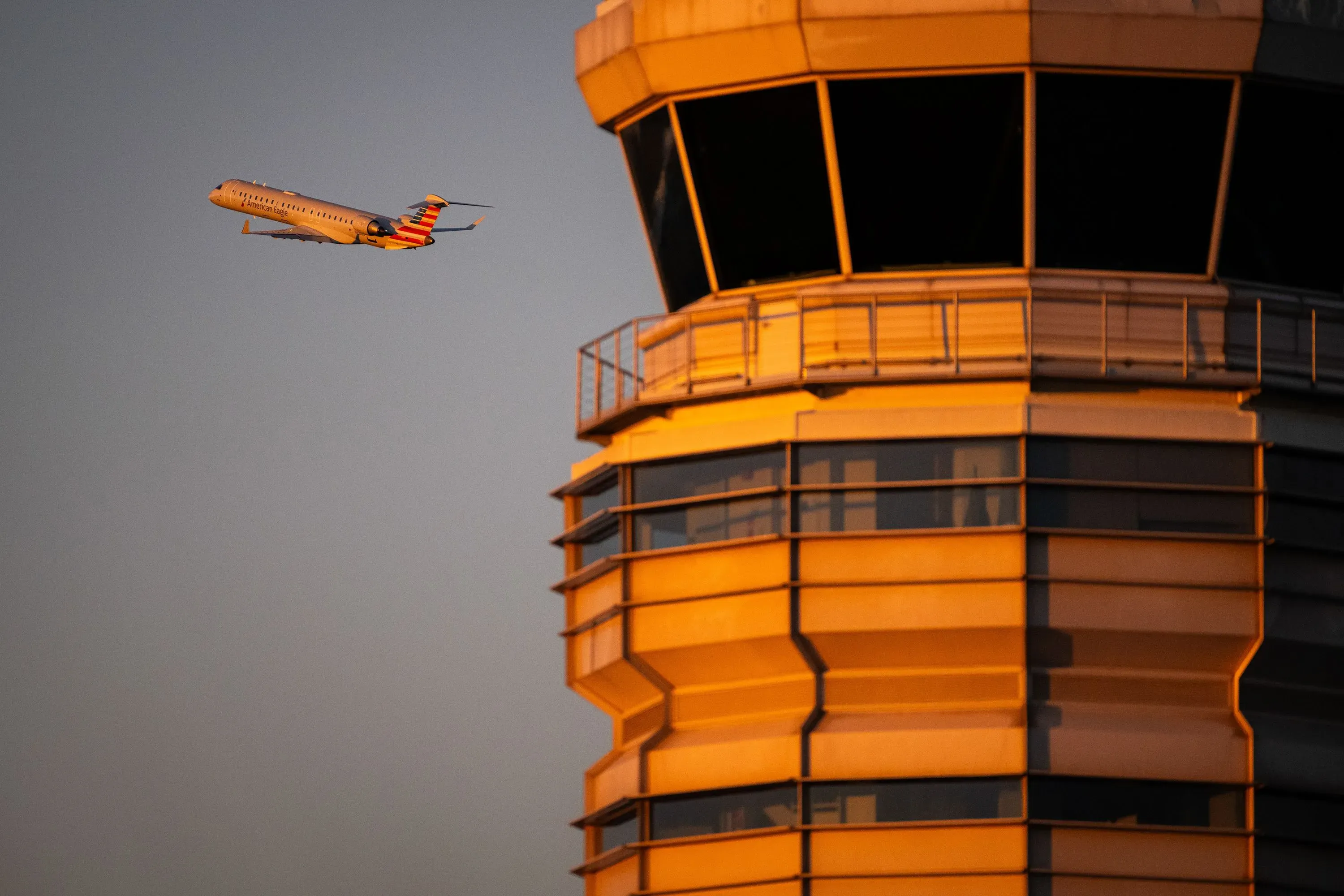 طائرة تحلق بجانب برج مراقبة الحركة الجوية، مما يبرز أزمة نظام المراقبة الجوية في الولايات المتحدة وتأثير الإغلاق الحكومي.