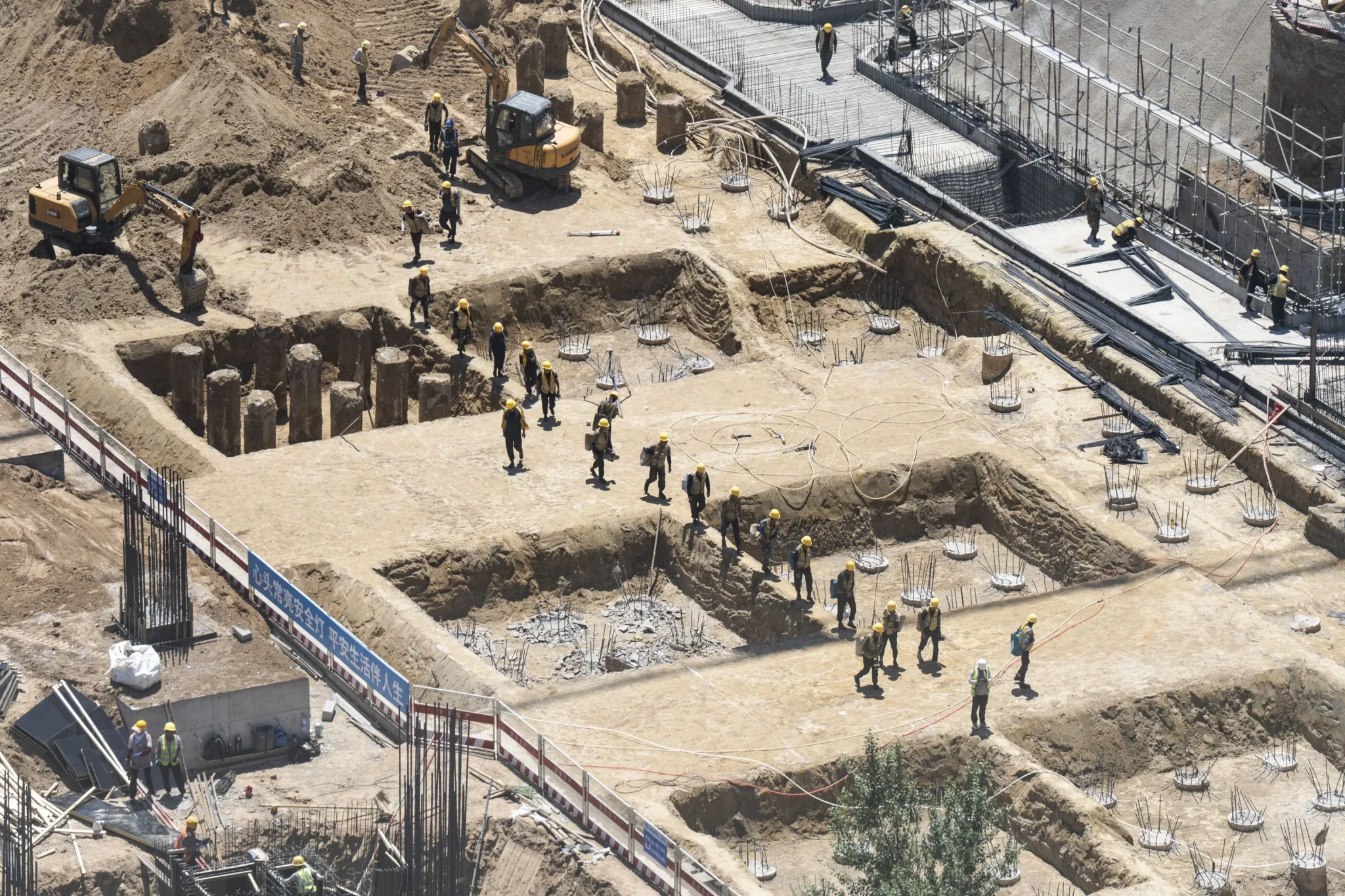 عمال بناء يرتدون خوذاً يشاركون في أعمال حفر وتشييد أساسات مركز بيانات في أولانكاب بالصين، ضمن جهود توسيع بنية الذكاء الاصطناعي والطاقة الخضراء.