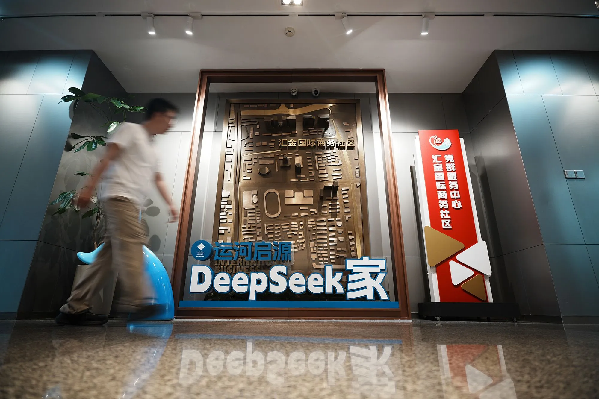شخص يمشي أمام شعار DeepSeek في مبنى مكتبي بالصين يعكس نمو نماذج الذكاء الاصطناعي الصينية المفتوحة المصدر.