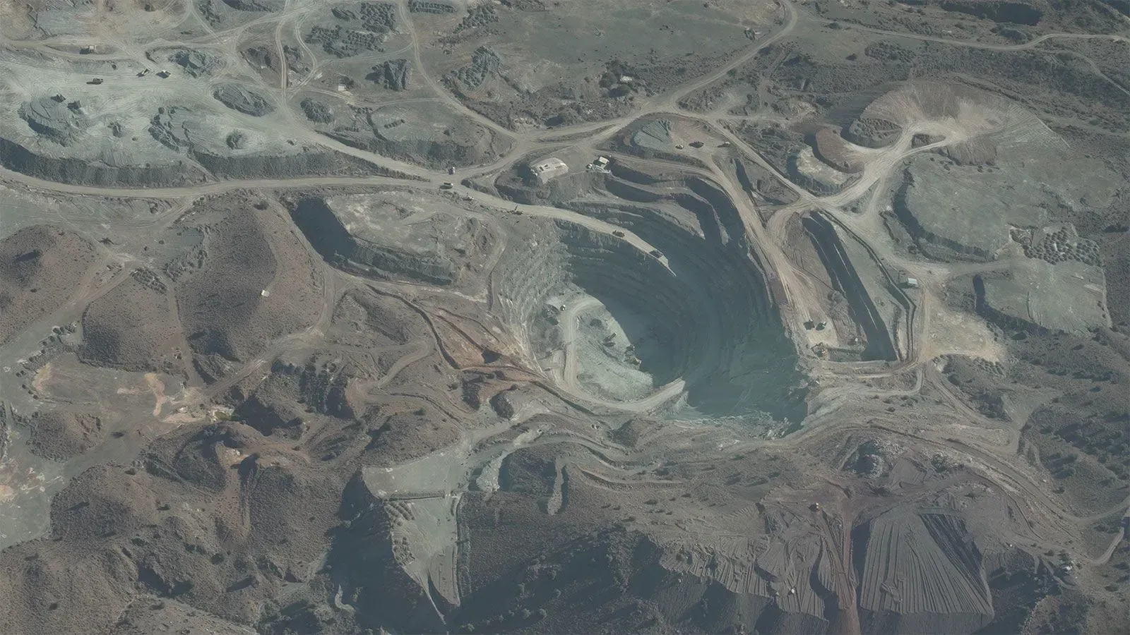 منجم محمد خيل للنحاس في باكستان، يظهر حفرة كبيرة محاطة بتضاريس وعرة، حيث يتم استخراج المعادن الثمينة.