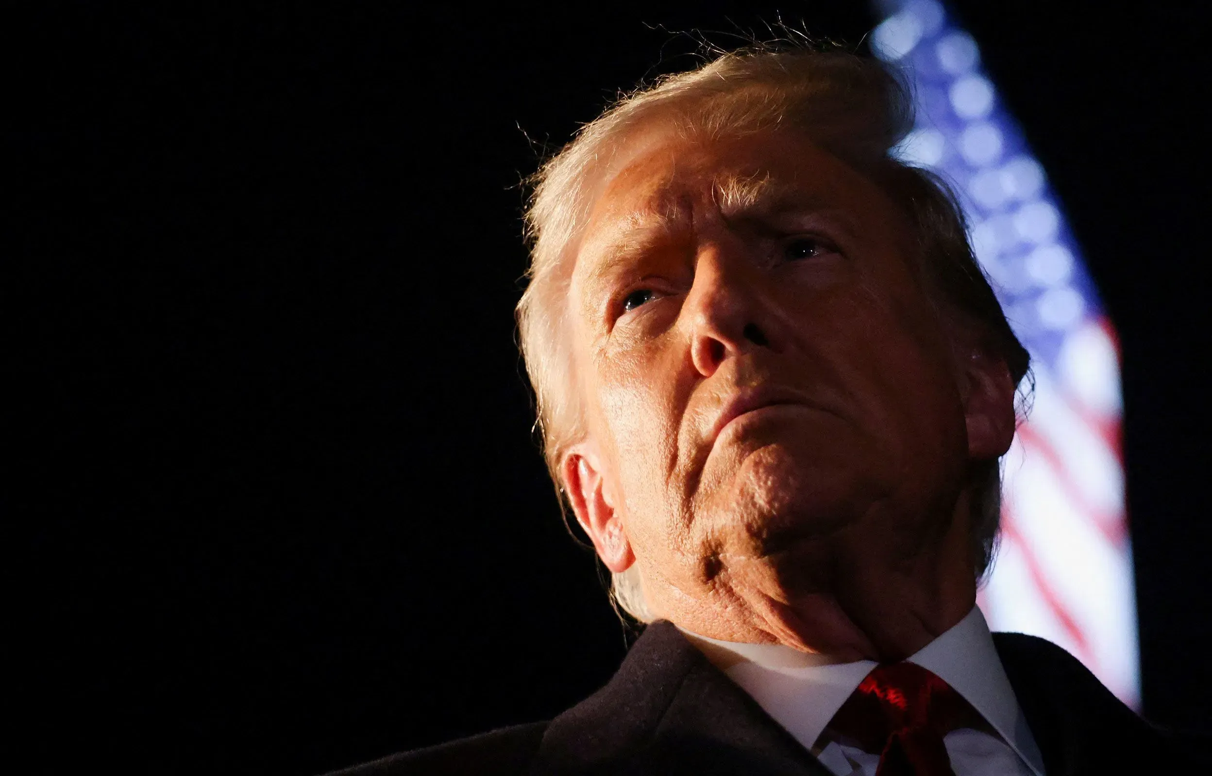 صورة قريبة لدونالد ترامب، يظهر فيها بملامح جدية، مع العلم الأمريكي في الخلفية، تعكس تصعيد الحرب على المخدرات في عهده.