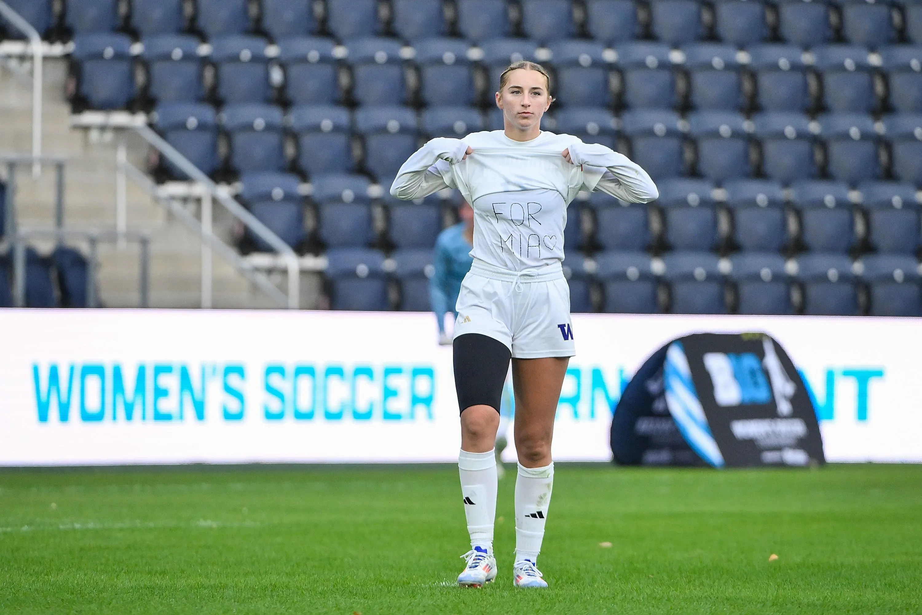 لاعبة كرة قدم ترتدي قميصًا مكتوبًا عليه "FOR MIAS" في ملعب رياضي، تعبيرًا عن الدعم والتكريم لحارسة المرمى الراحلة ميا هامانت.