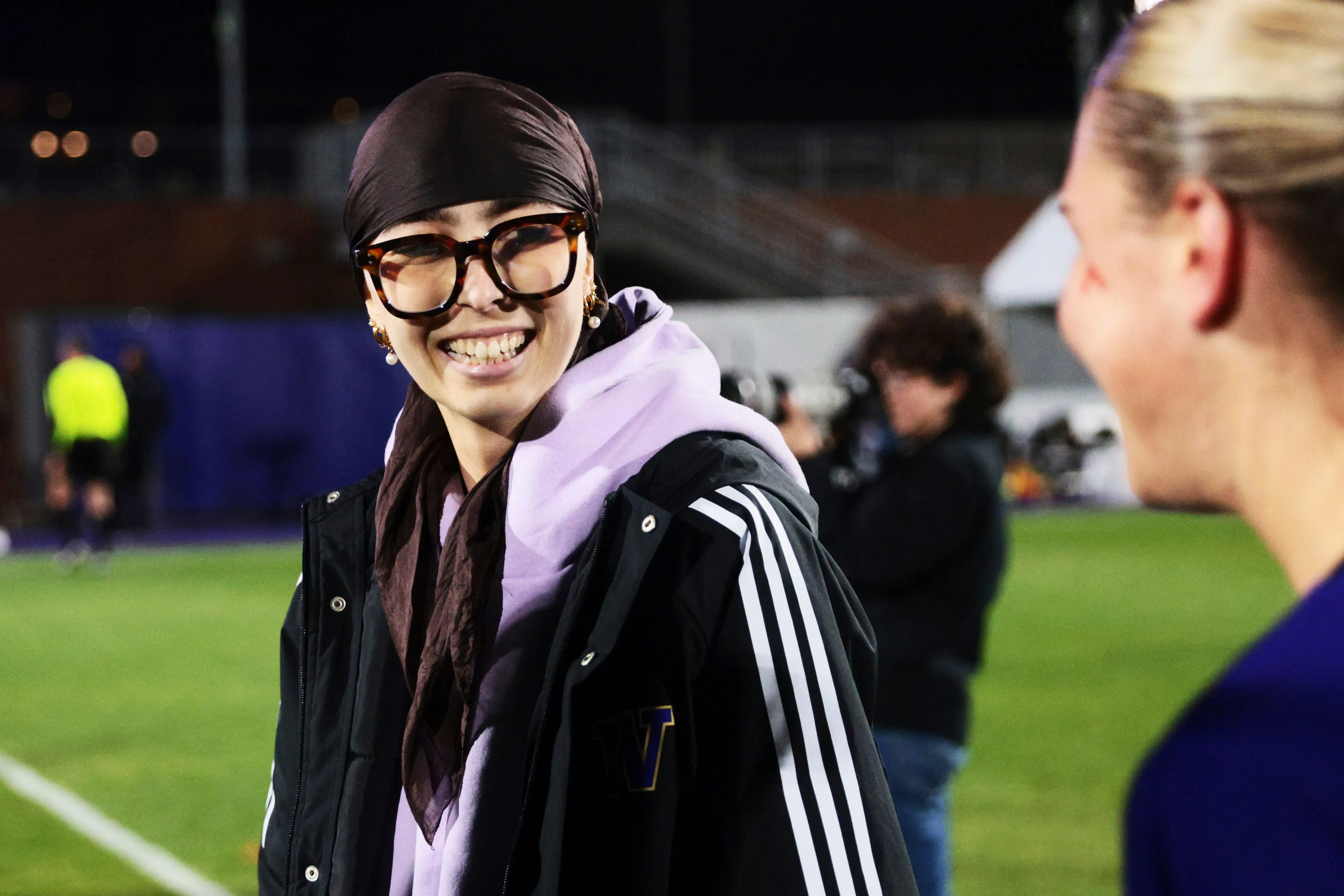 ابتسامة ميا هامانت، حارسة مرمى جامعة واشنطن، أثناء حديثها مع زميلتها على أرض الملعب، تعكس روح الفريق والتضامن في مواجهة التحديات.