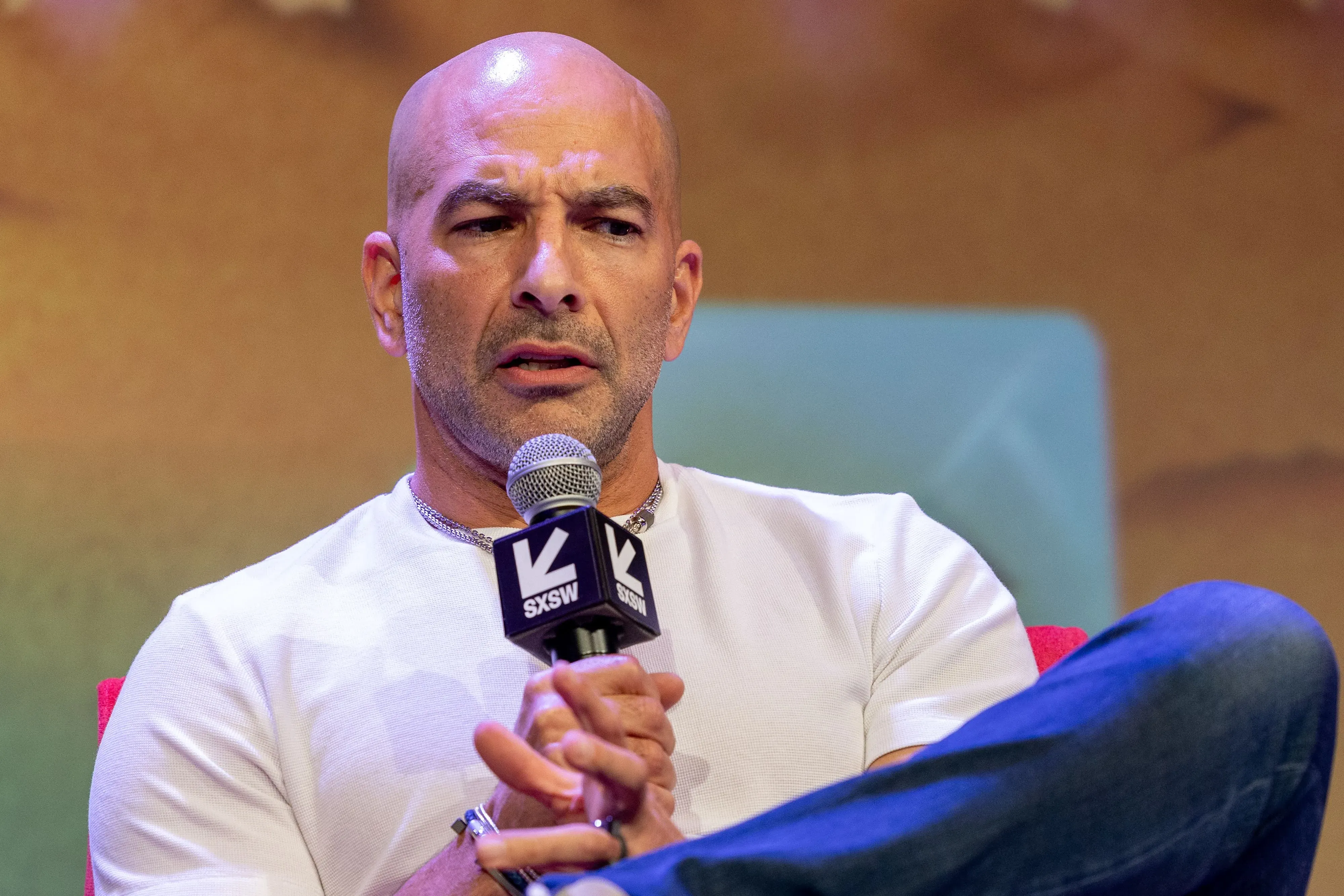 رجل يتحدث في حدث عام، مع تعبير وجه جاد، في خلفية غير واضحة. الصورة تعكس الأجواء المثيرة للجدل حول ملفات جيفري إبشتاين.