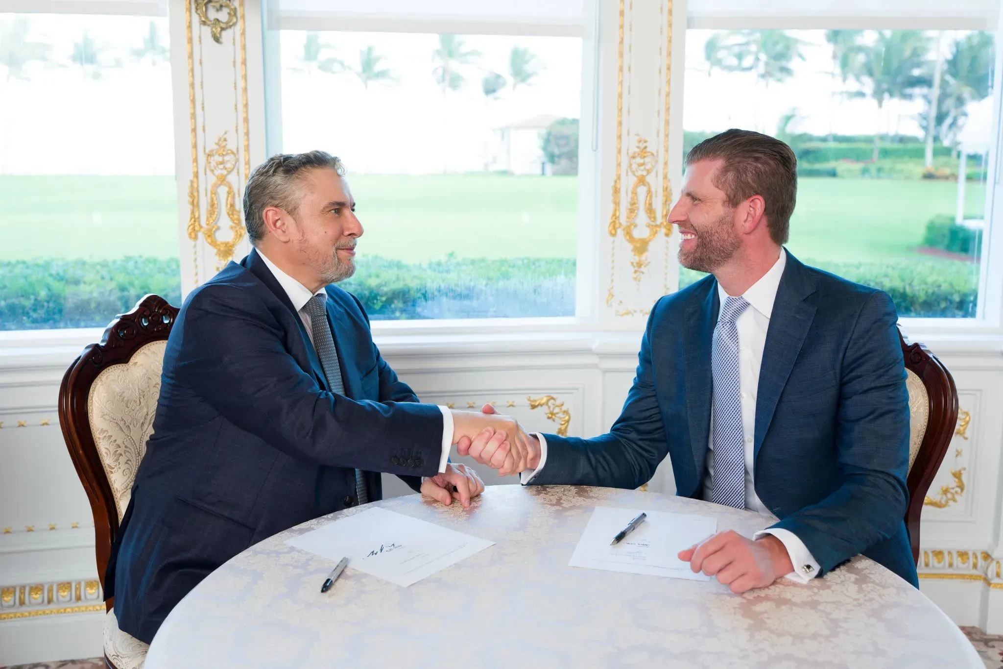 توقيع اتفاقية بين مطور عقاري ورجل أعمال في مكان فاخر، مع إطلالة على المساحات الخضراء. المشروع المقترح هو برج ترامب في جولد كوست.